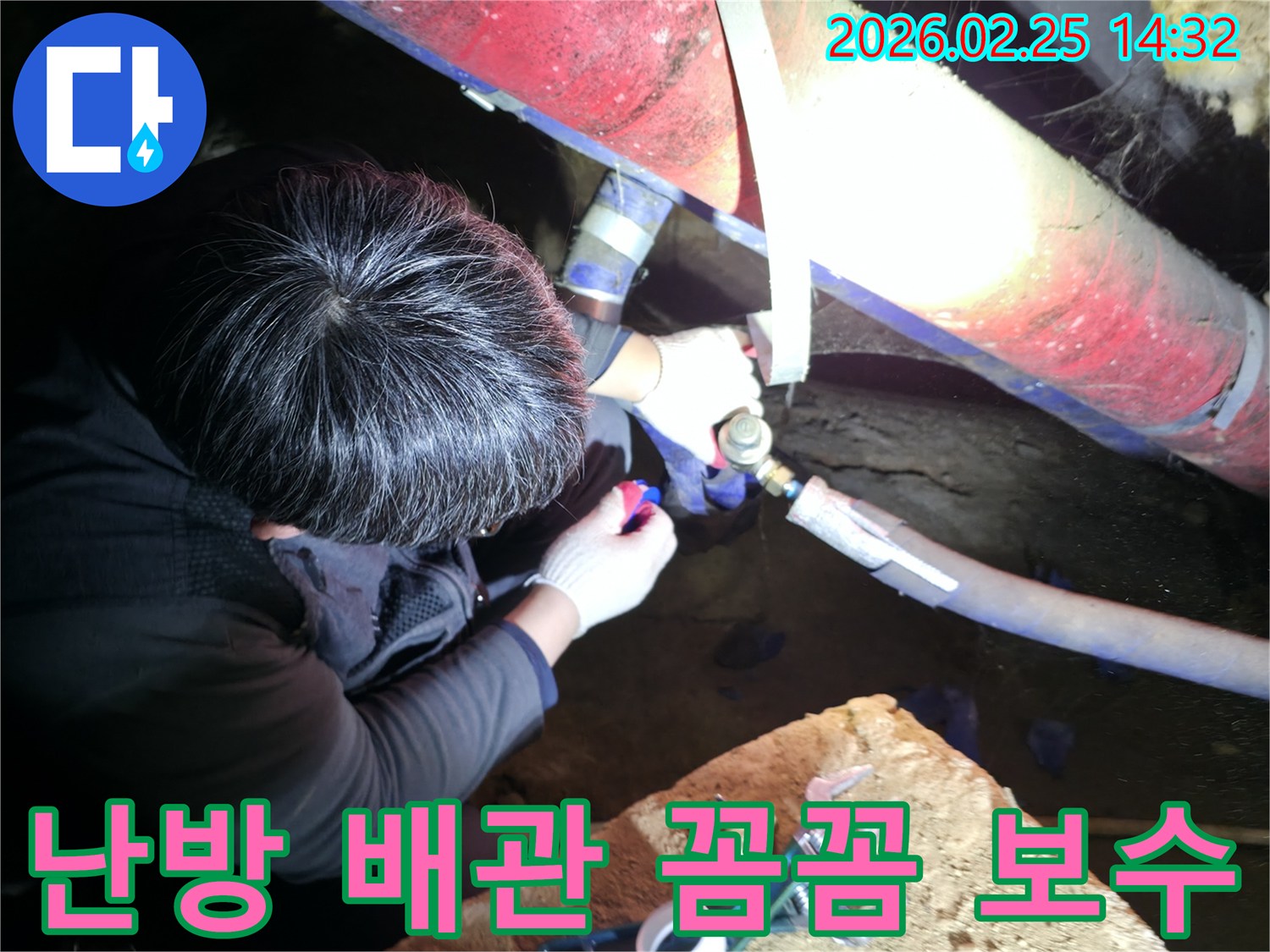 숙련된 누수 기술자가 좁은 공간에서 손전등을 비추며 난방 배관 연결 부위를 정밀하게 점검하고 꼼꼼하게 보수하고 있습니다-난방누수해결-전문가보수