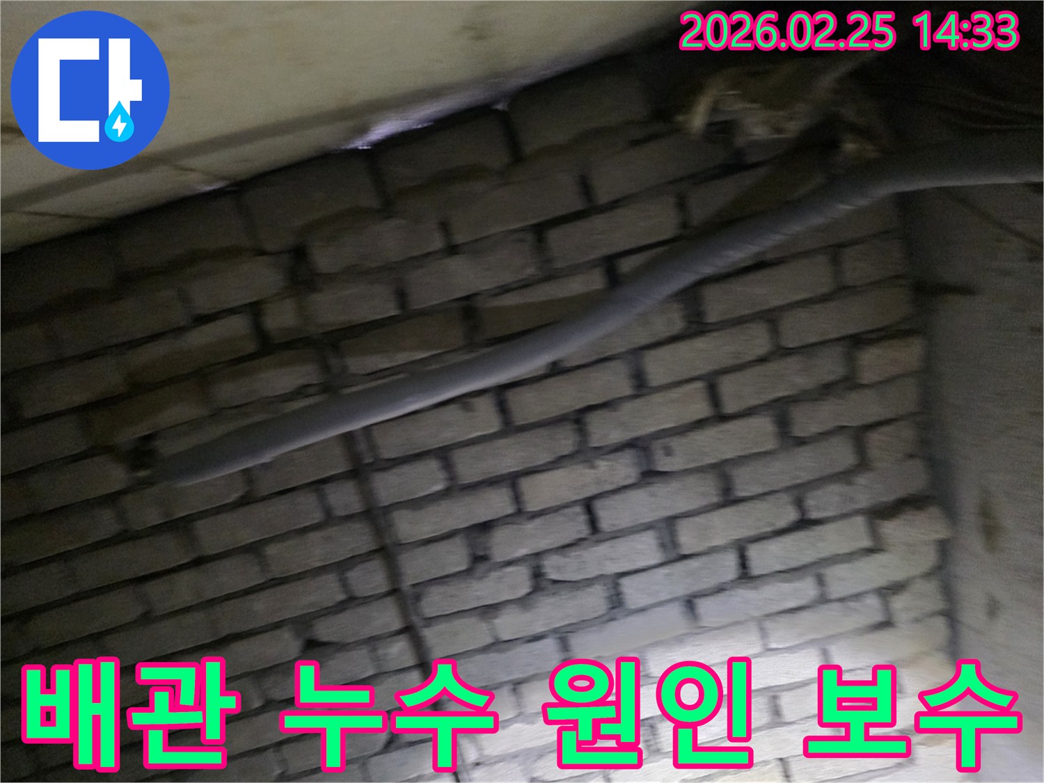 어두운 벽돌 벽면을 배경으로-단열된 배관과 함께-누수 원인을 파악하고-보수 작업을 준비하는 현장 모습입니다.