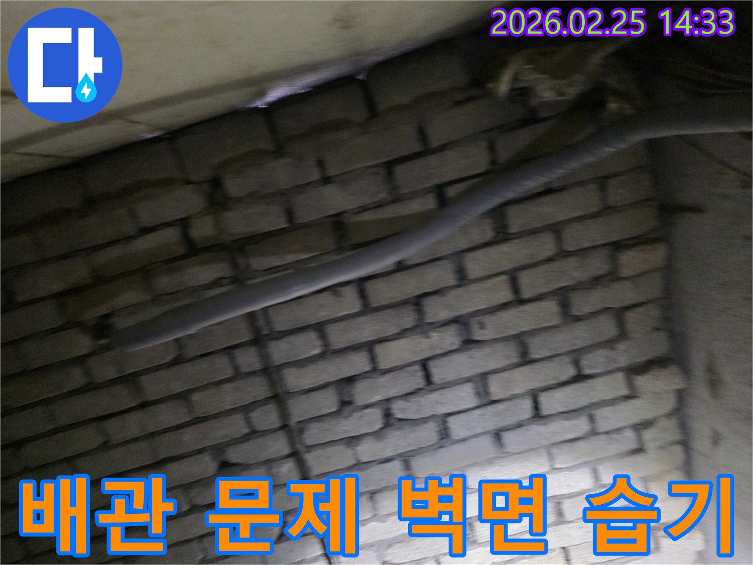 어두운 벽돌 벽면을 배경으로-단열된 배관과 함께-누수로 인한 벽면 습기를-제거하기 위해 검사되는 현장 모습입니다.
