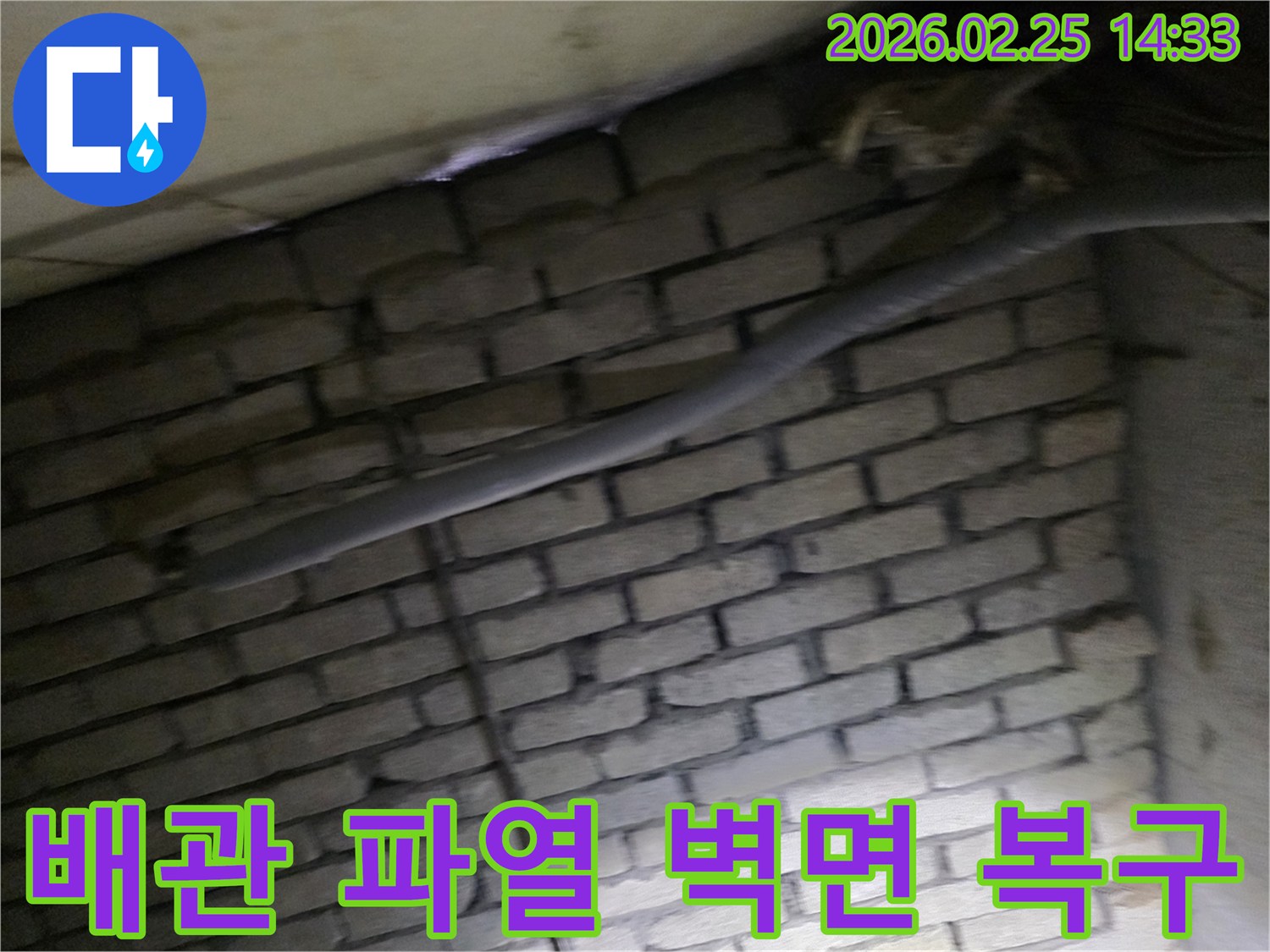 어두운 벽돌 벽면을 배경으로-파열된 배관과 함께-침수 피해를 확인하기 위해-정밀하게 검사되는 현장 모습입니다.