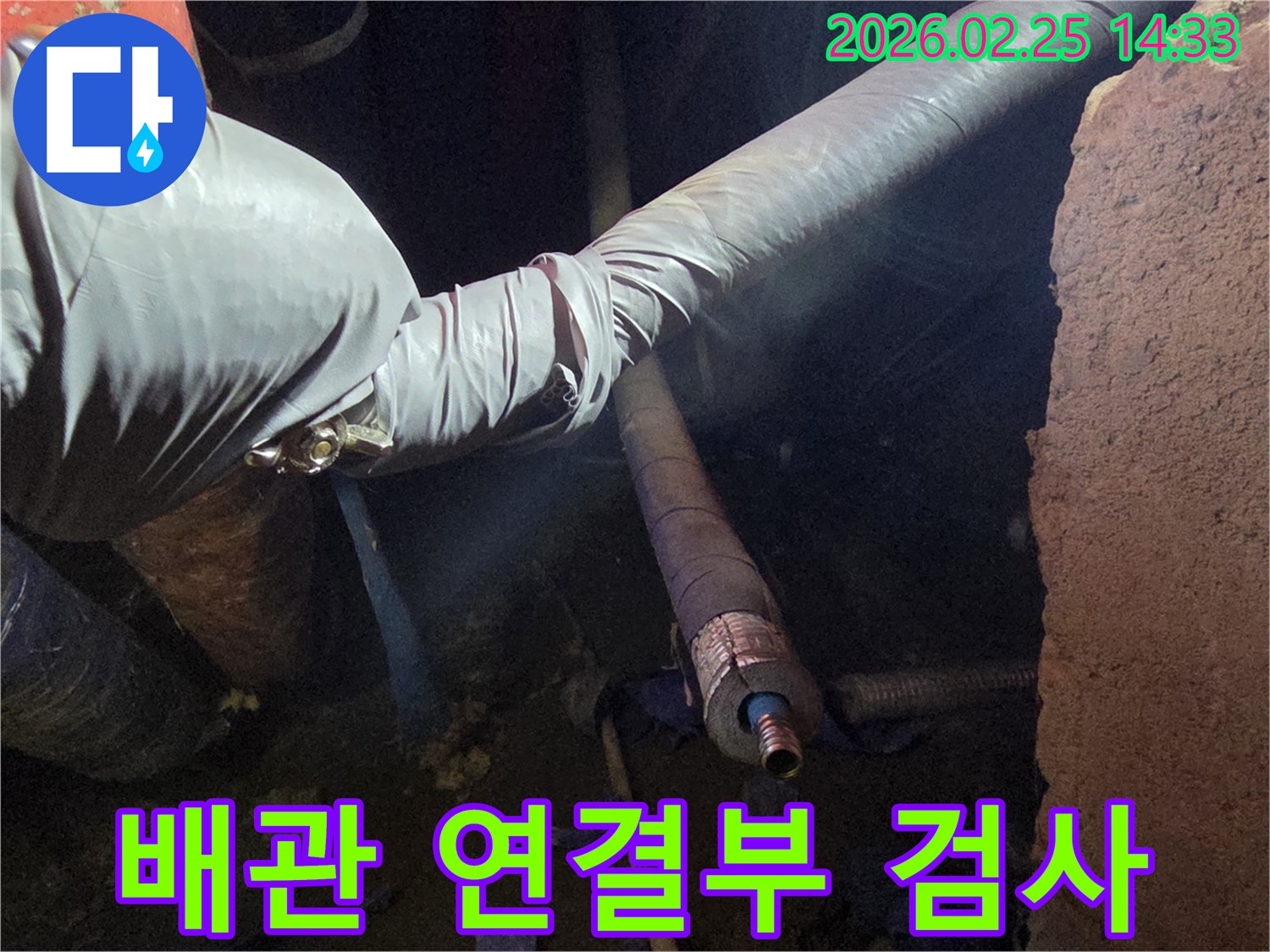 어두운 작업 공간에서-장갑을 낀 손이-배관의 연결 부위를-세심하게 검사하며-누수 원인을-파악하는 모습입니다