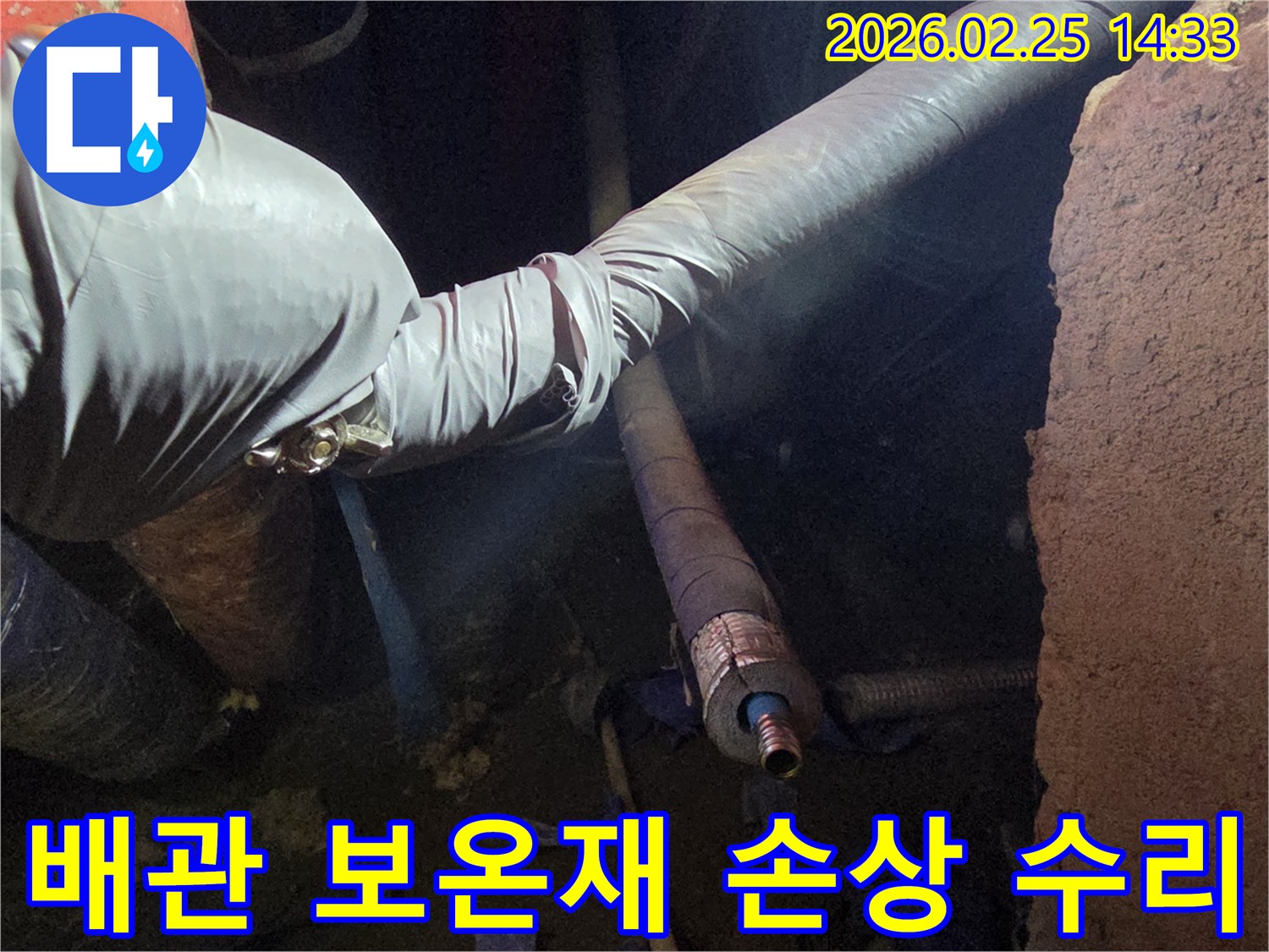 어두운 작업 공간에서-장갑을 낀 손이-손상된 보온재를 제거하고-새로운 단열재로-배관을 감싸는-모습입니다