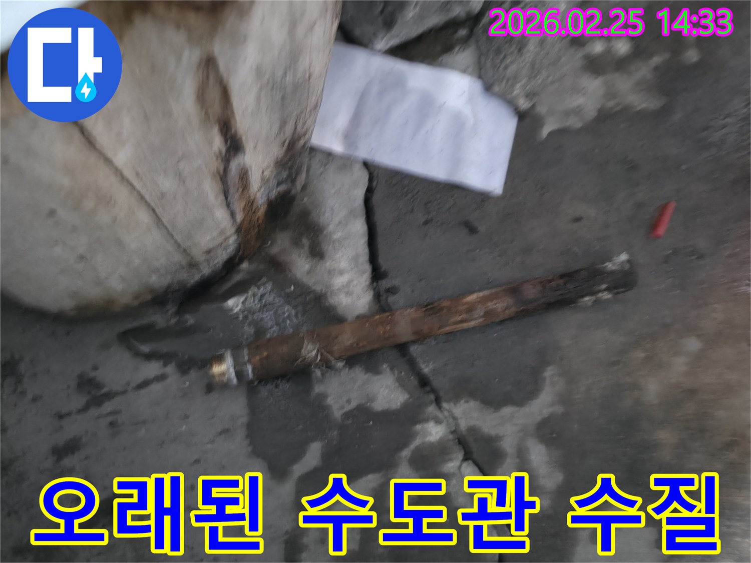 오래되어 녹슬고-파열된 수도관이-젖은 콘크리트 바닥에 놓여있는-누수 현장 사진입니다.
