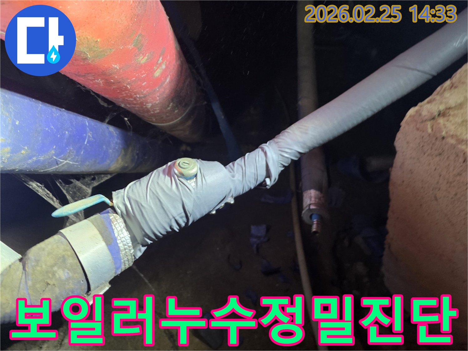 이 이미지는 누수 탐지를 위해 배관에 압력 측정 장비를 연결하는 전문 엔지니어의 모습을 보여줍니다-정확한 누수 지점을 찾기 위한 핵심 과정입니다