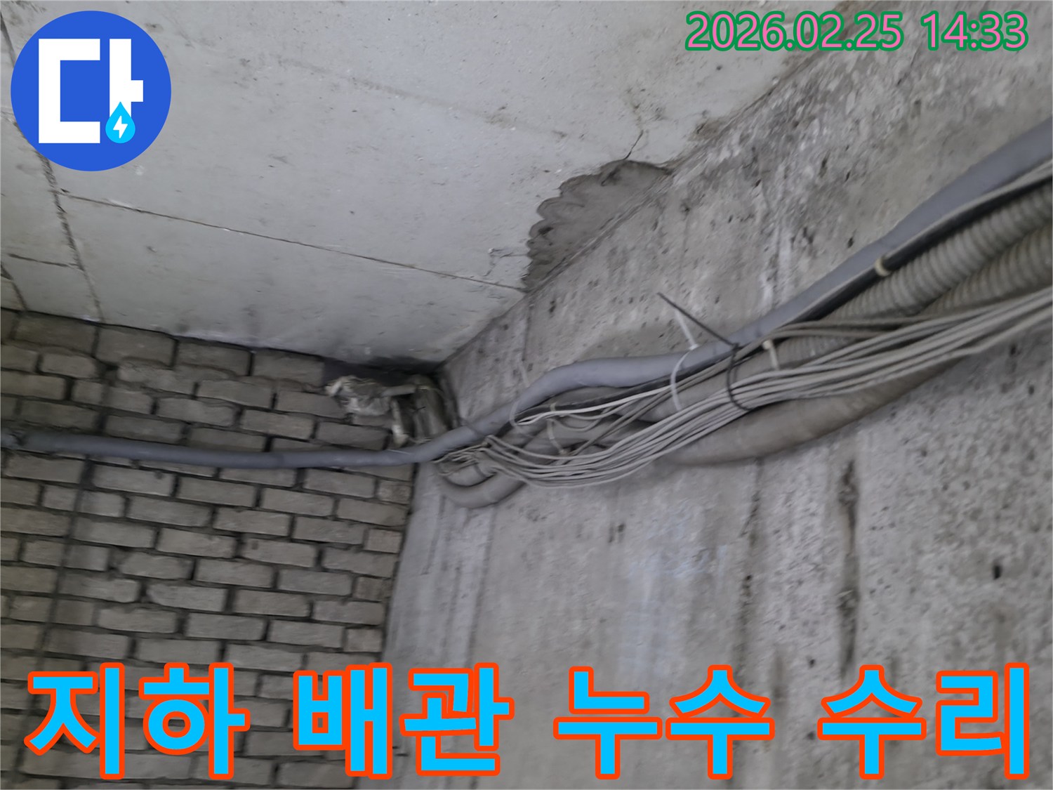 지하 벽면의-콘크리트와-벽돌 벽이 만나는-지점에서-발견된-오랜 누수로 인한-짙은 물자국과-주변 배관