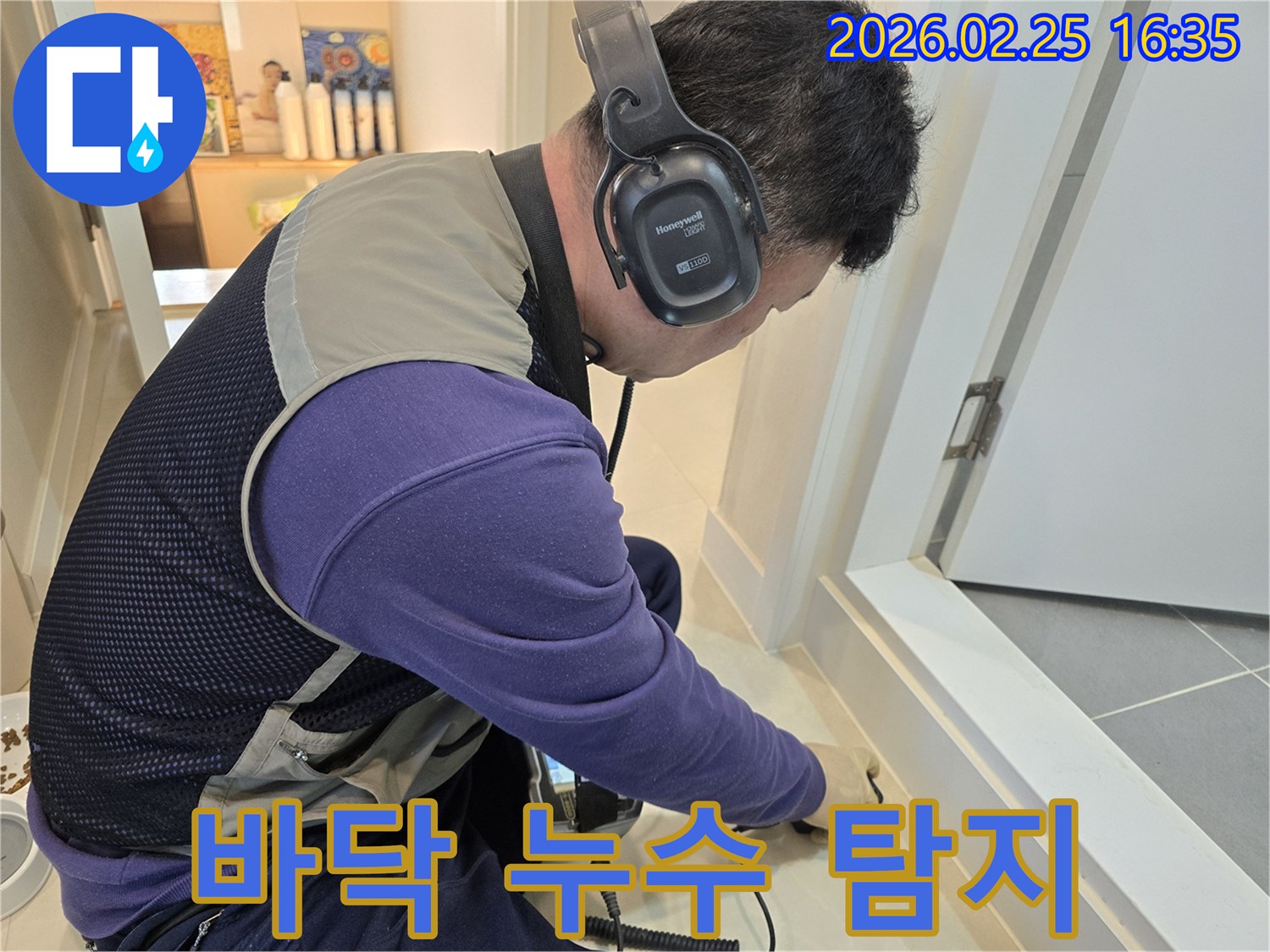 누수 엔지니어가-특수 헤드폰과 탐지기로-바닥 타일 아래의-미세한 누수음을-집중해서 듣고 있습니다