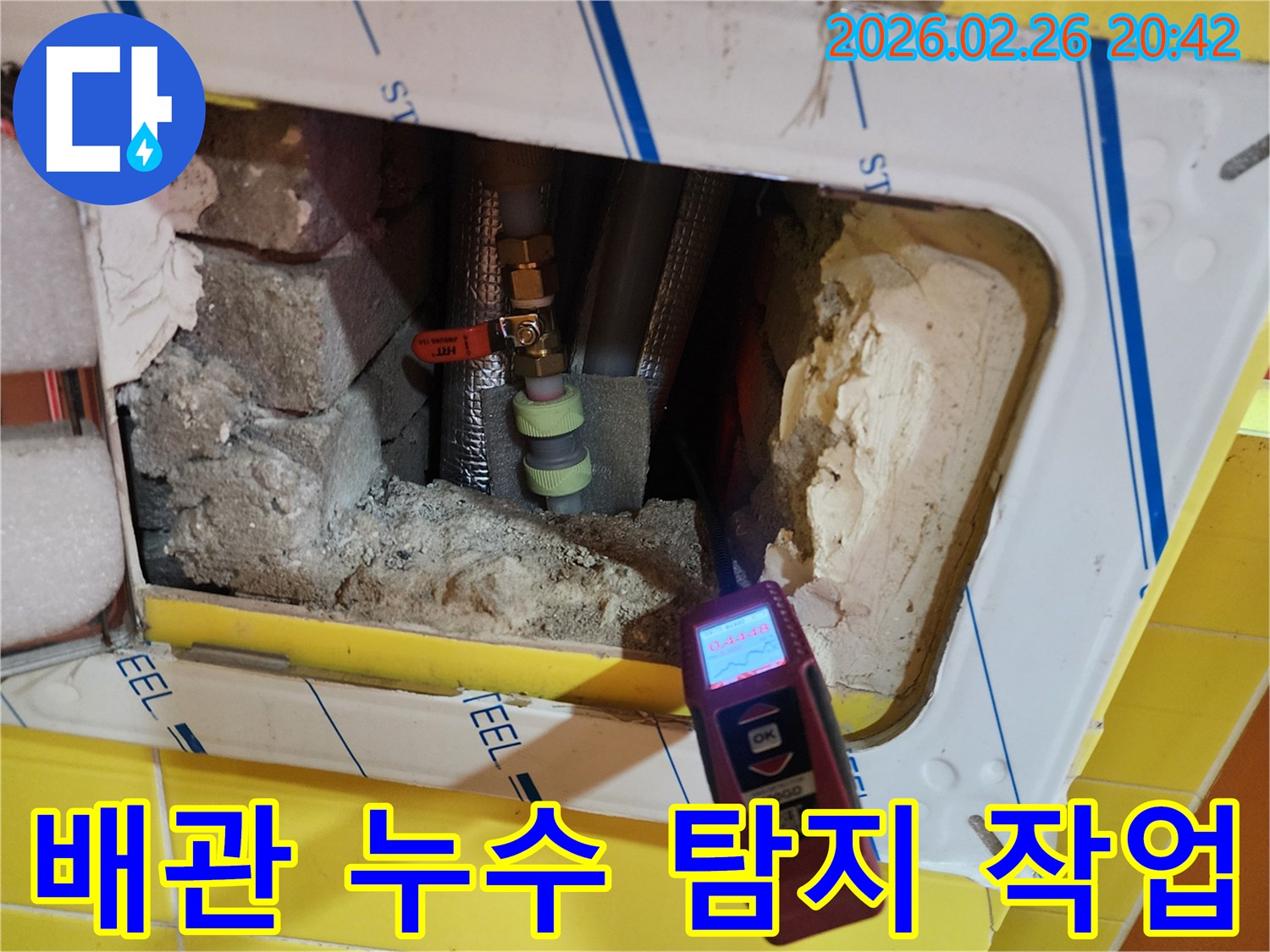 누수 탐지 엔지니어가-특수 장비로-배관 주변의 습기를 측정하며-누수 지점을 찾는 장면