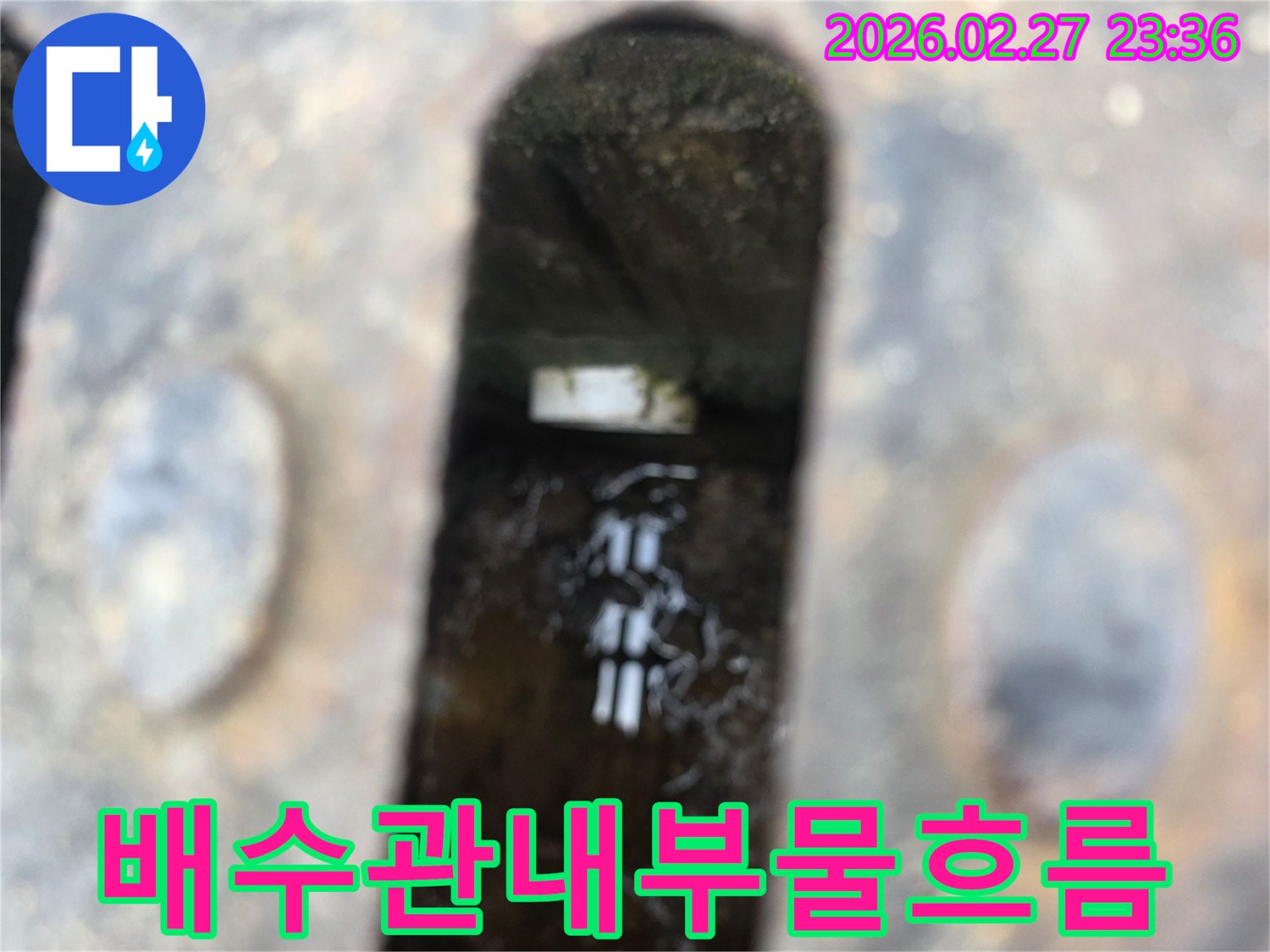 녹슨-철제-배수구-아래-고인-물과-물속에-반사되는-빛-그리고-배관-일부가-보이는-사진