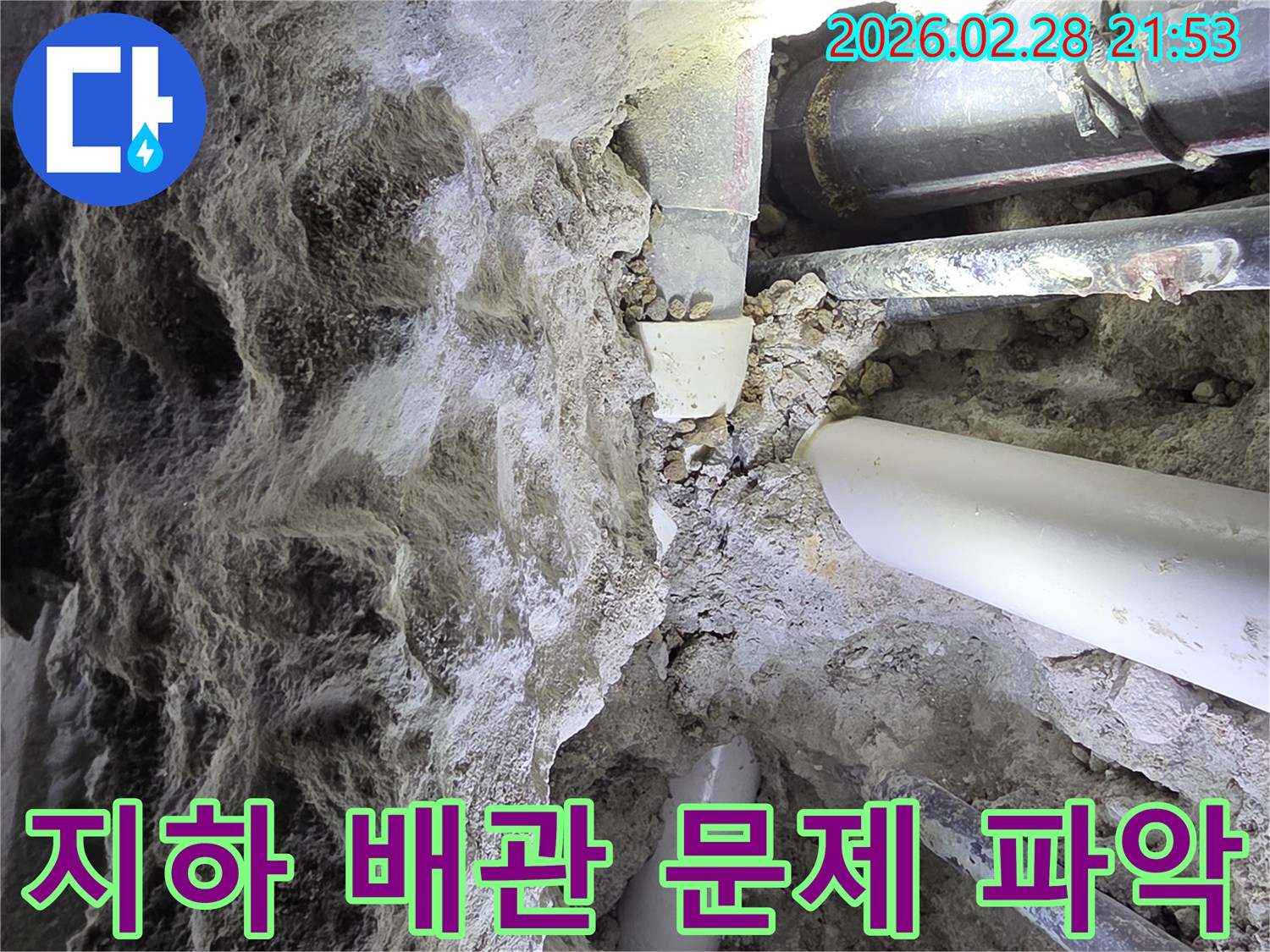 어두운 공간에서-흙과 자갈 속에 묻힌-다양한 배관들의-손상 여부를-면밀히 파악하는 누수 전문가의 모습