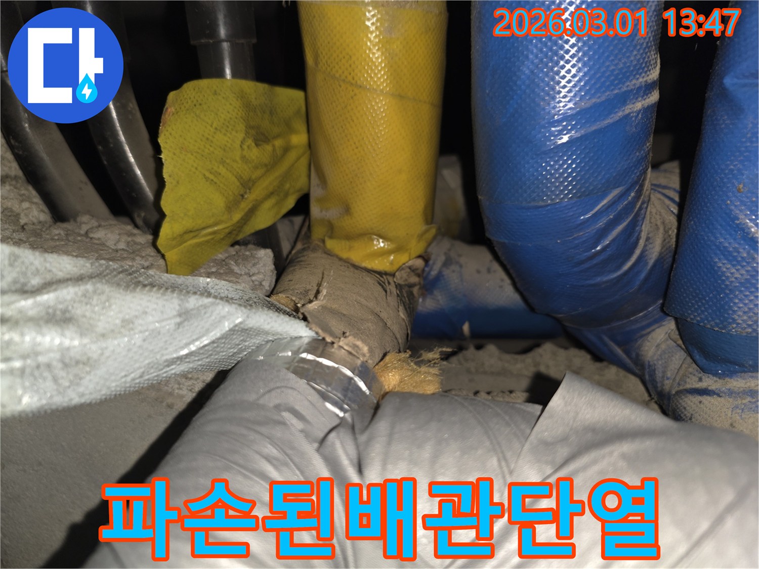 배관 주변의 보호막이 훼손되어-내부 단열재가 노출된 상태를 촬영한 사진입니다.