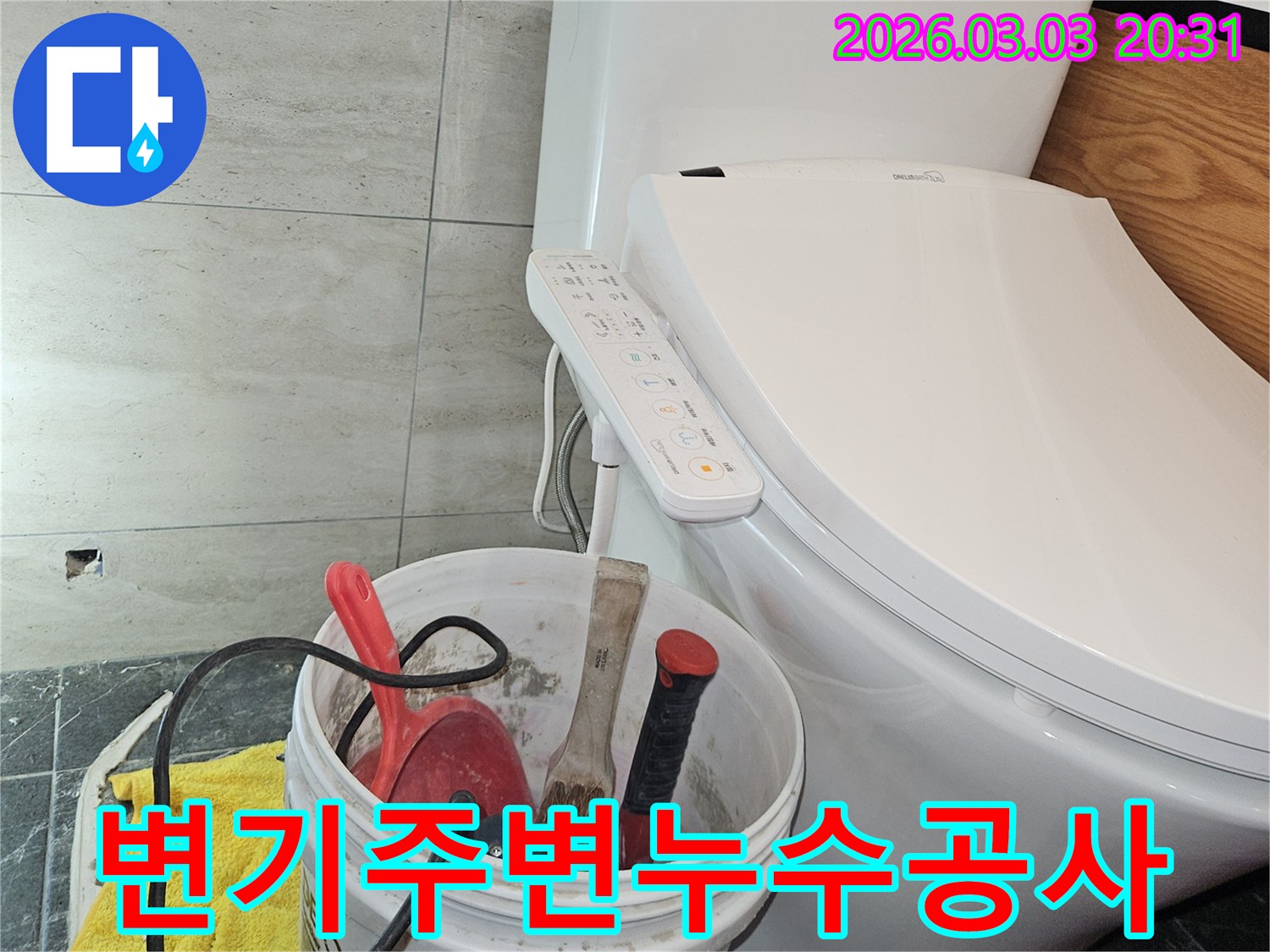 변기 옆에 놓인 작업 도구들이-화장실 바닥에서 발생한 누수를-해결하기 위한 준비 과정을 나타냅니다.