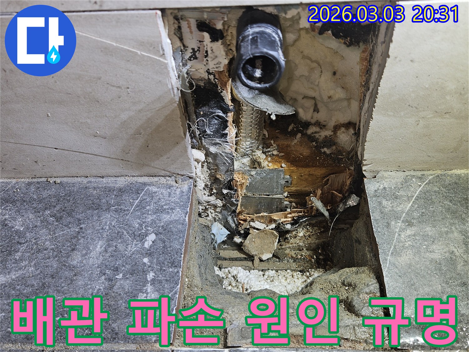 타일이 제거된 벽면 안쪽에서 누수 흔적과 함께 손상된 배관이 노출된 모습