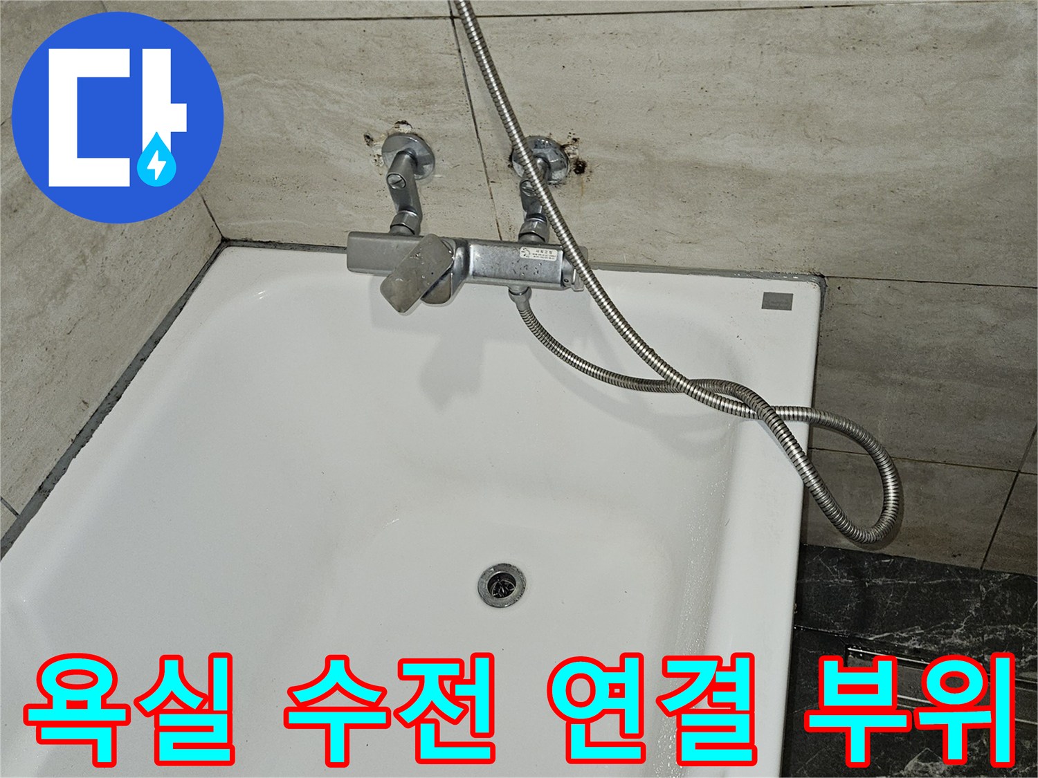 하얀 욕조 옆 벽면 타일에 설치된 급수용 밸브와 호스
