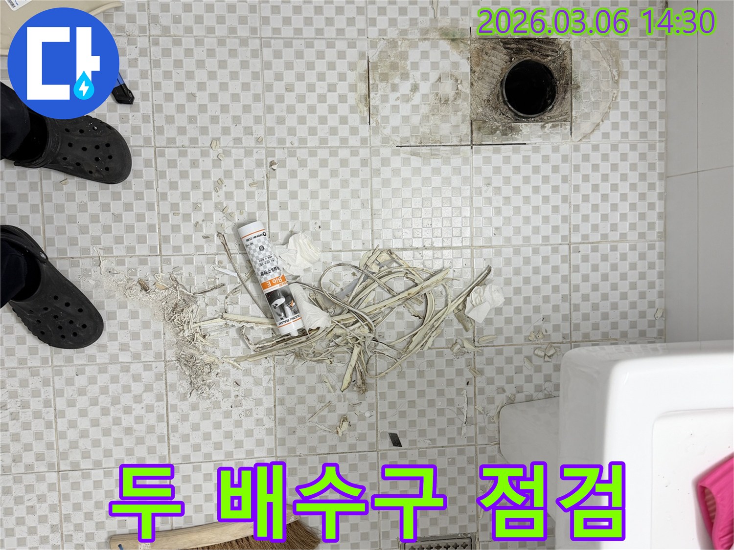 주택 욕실 바닥의-크고 작은 두 배수구 주변을-누수 흔적과 오염 여부를-면밀히 점검하는 모습