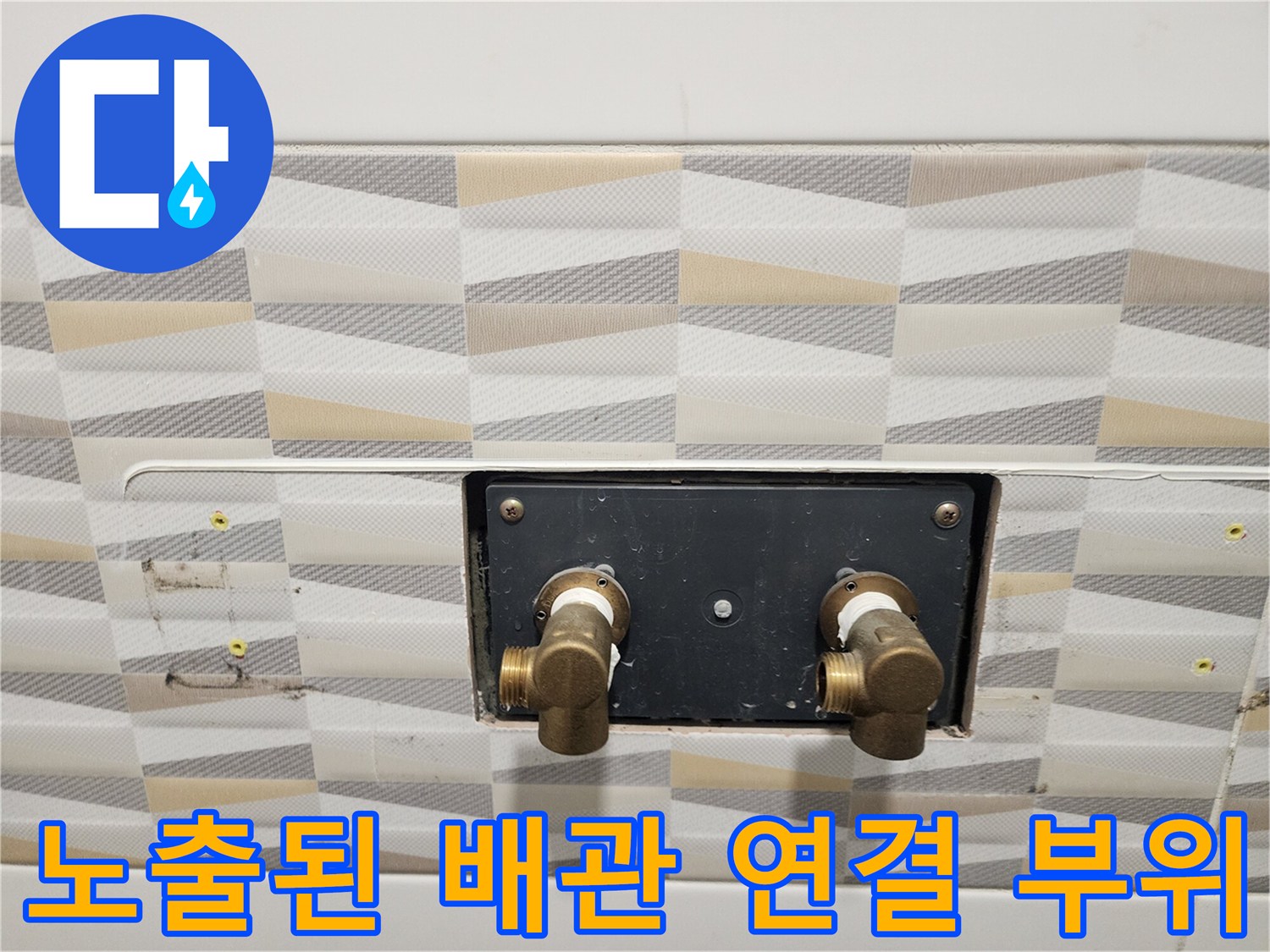 욕실 타일 벽면 아래에 노출된 온수 및 냉수 공급용 배관