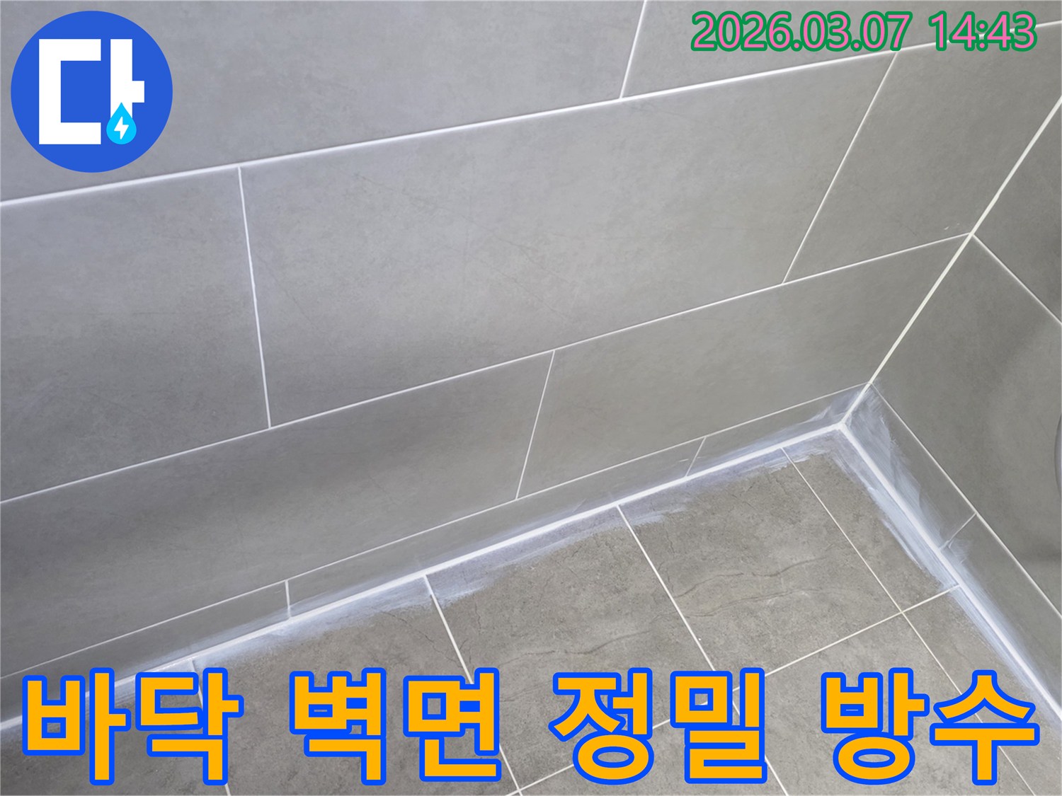 회색 타일로 된-건물 화장실의-바닥과 벽면의-경계선을-새로운 실리콘으로-튼튼하게 마감하여-누수를 방지한 사진