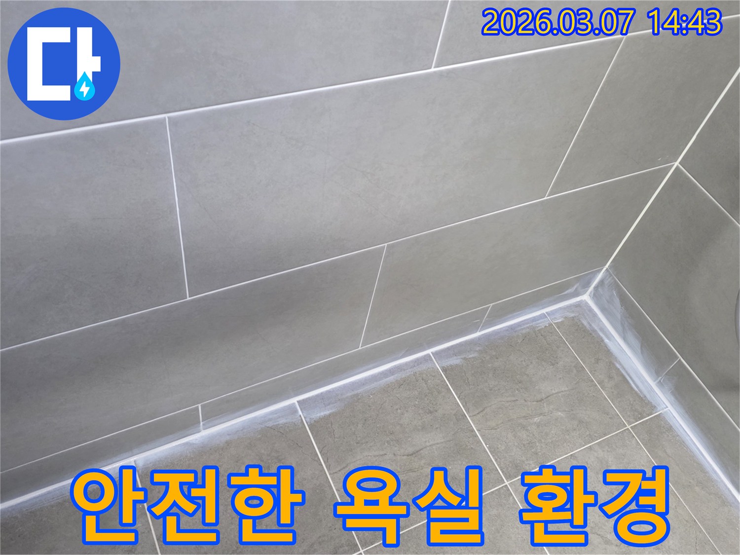 회색 타일로 마감된-아파트 화장실의-벽과 바닥 경계면에-새로운 실리콘이-깔끔하게 시공되어-안전하고 쾌적한 환경을 조성한 모습