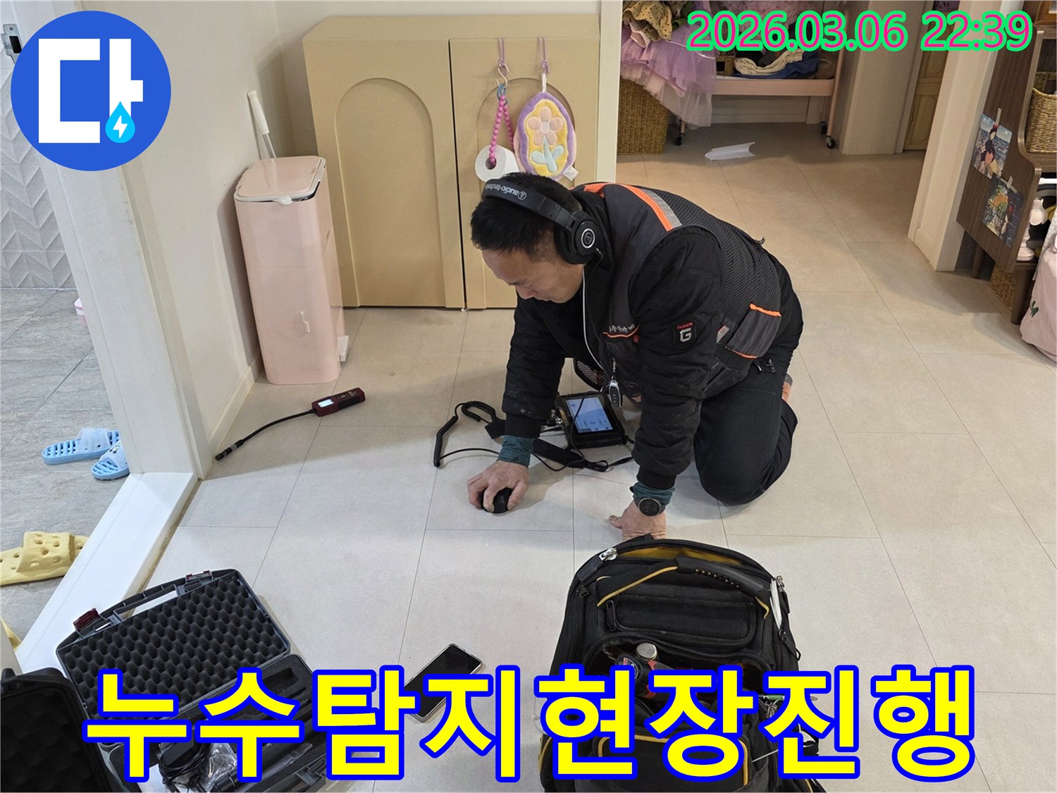 바닥-누수-탐지를-위해-전문-기술자가-헤드폰과-탐지기를-사용하여-집중적으로-작업하는-장면입니다.
