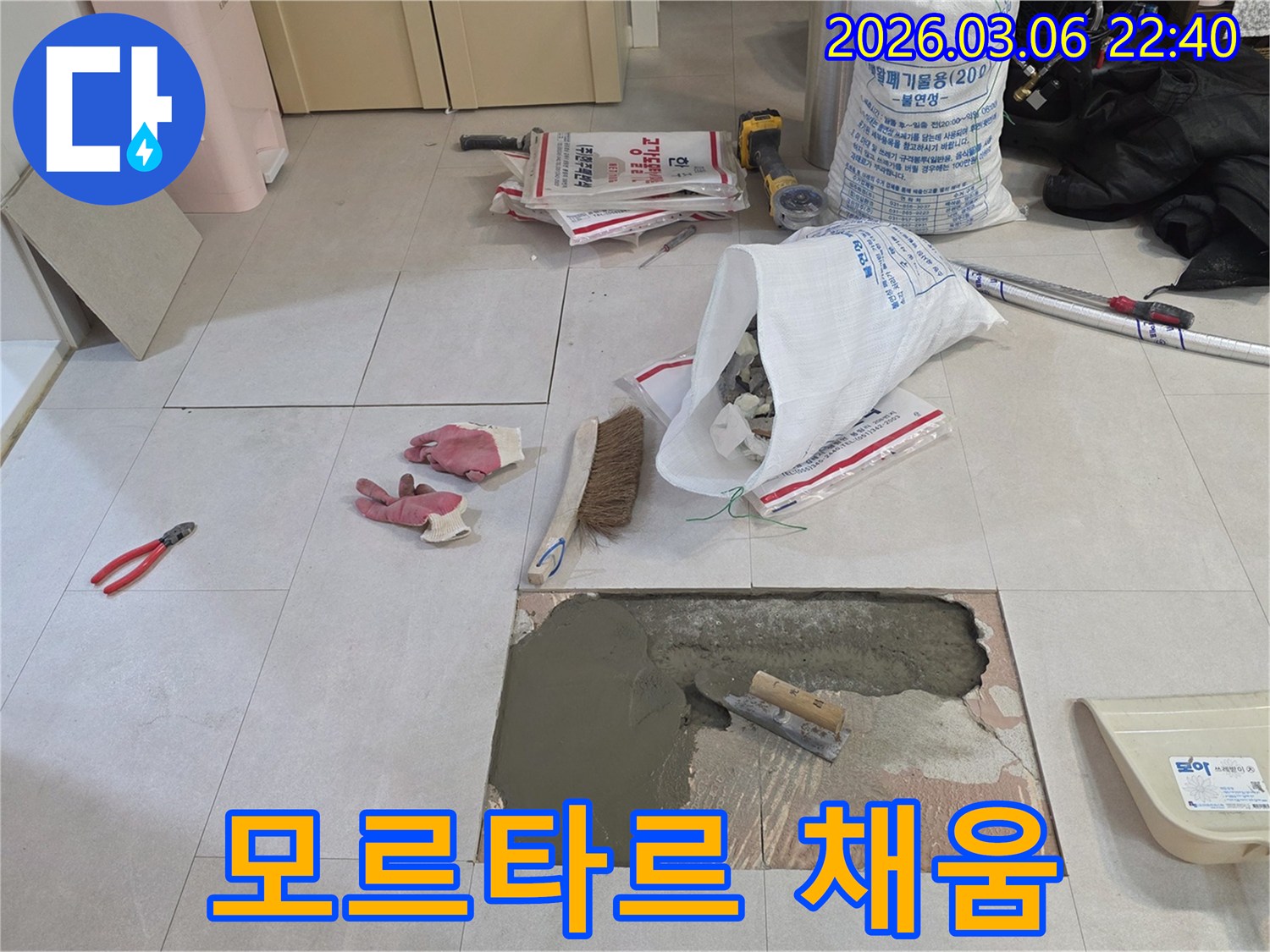 아파트 누수 공사 중-손상된 바닥면에-모르타르를 채워 넣으며-복구 작업을 진행하는-모습입니다.