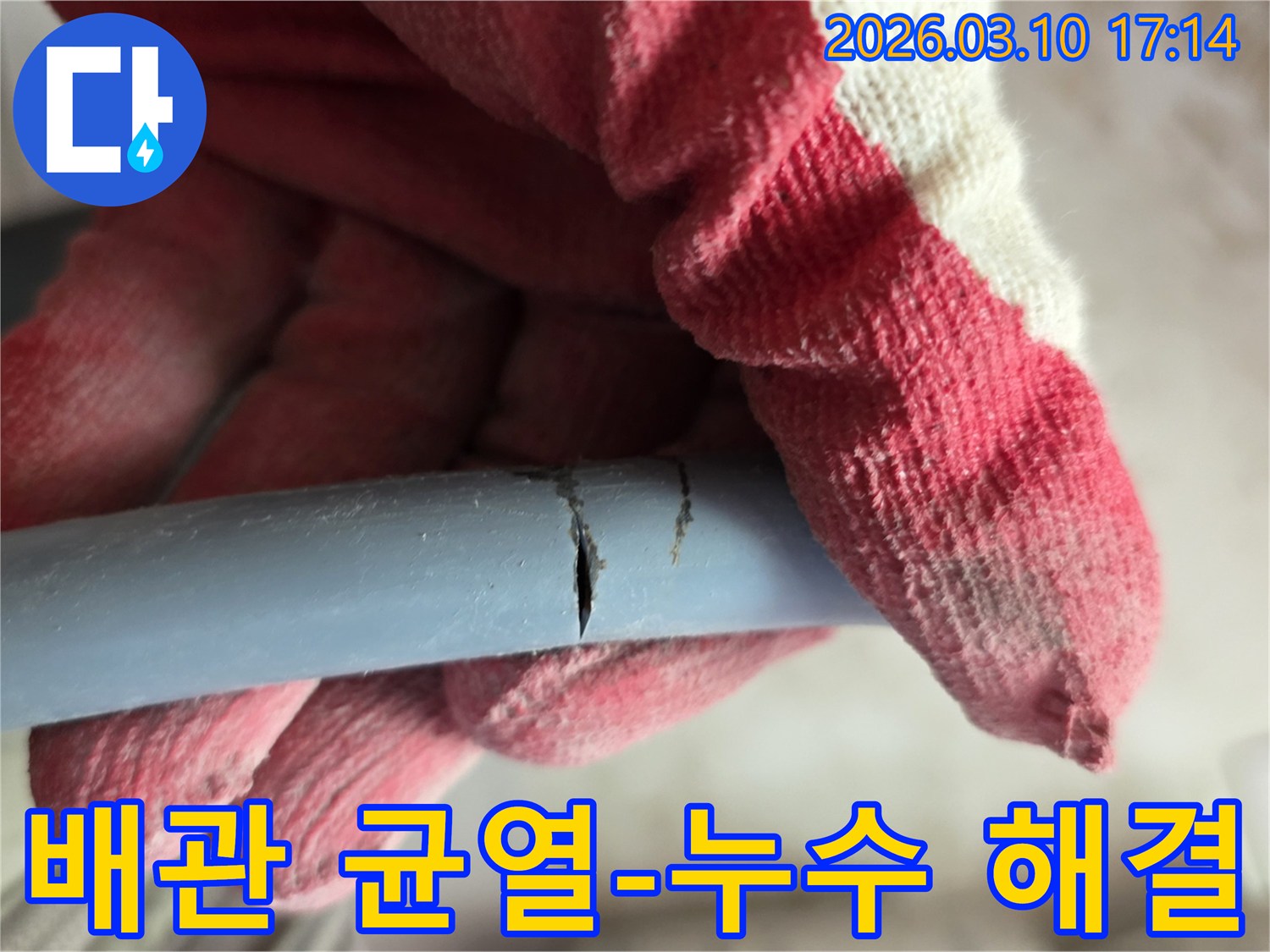 작업용 장갑을 낀 손이-균열이 생긴 배관을 잡고-누수 지점을 확인하고 있습니다