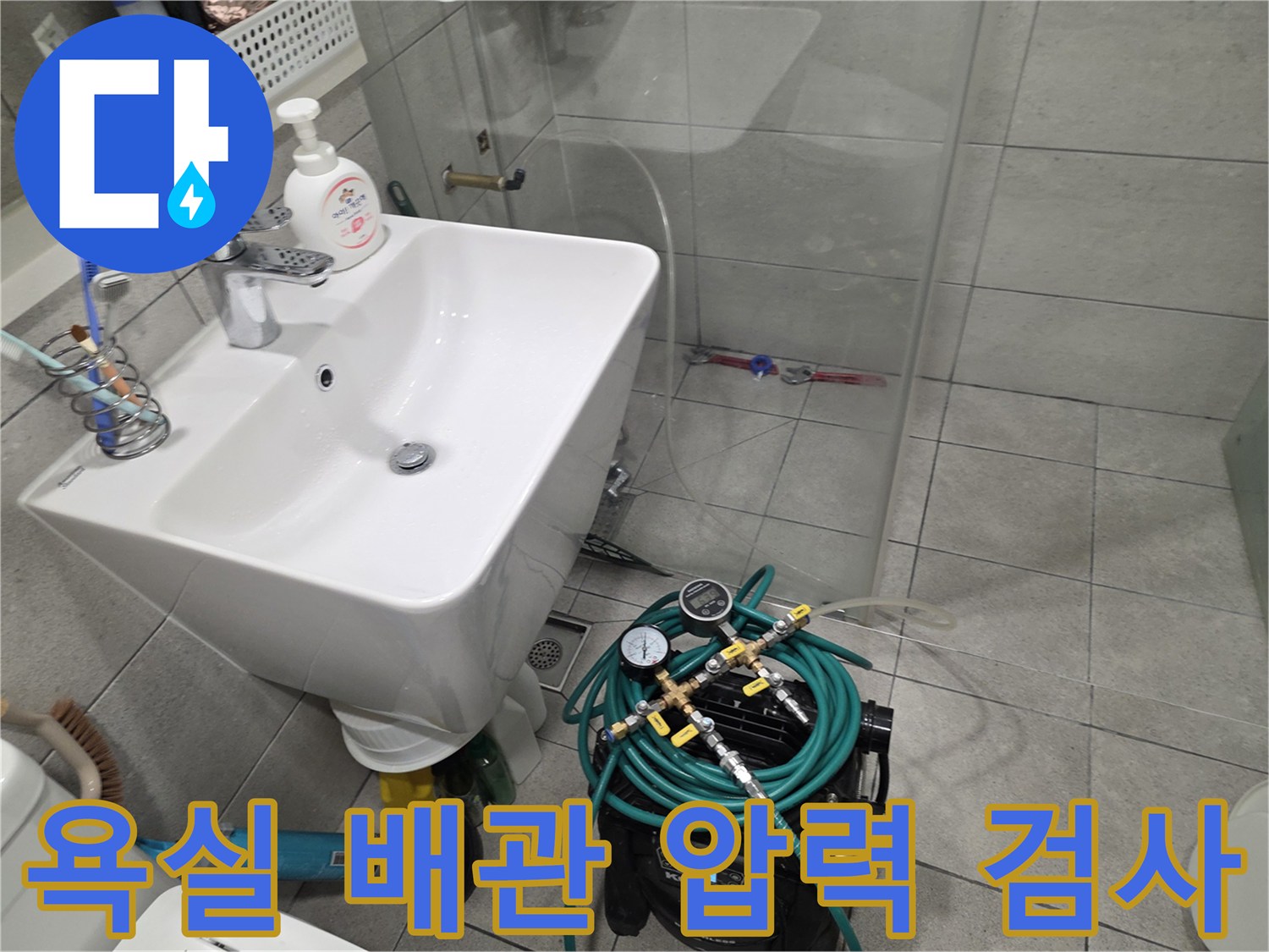 화장실 세면대 아래에 설치된 공압 테스트 장비와 게이지