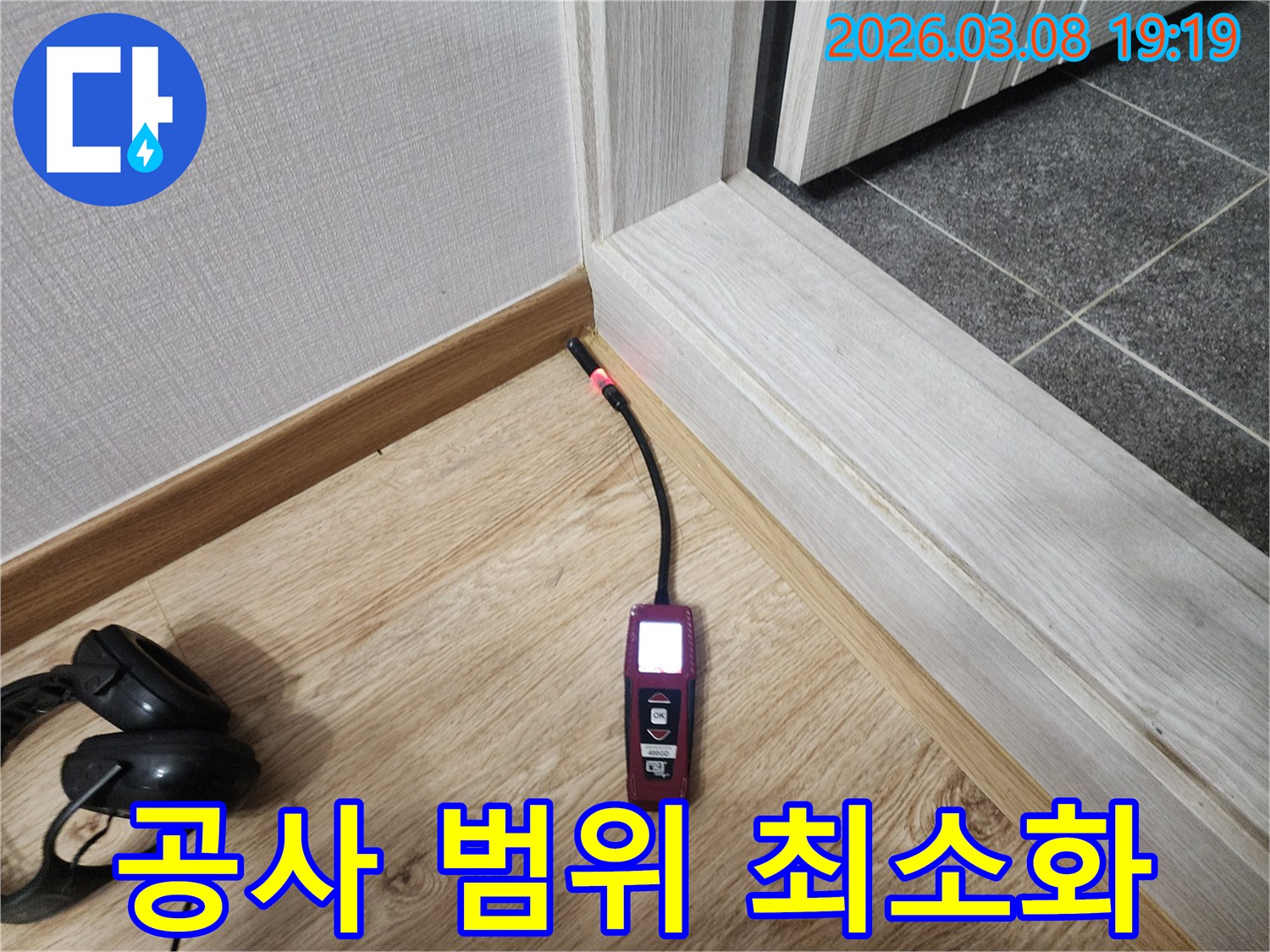 나무-바닥과-벽면-경계에서-누수탐지기가-붉은색-불빛으로-누수-위치를-정확히-지목하는-사진