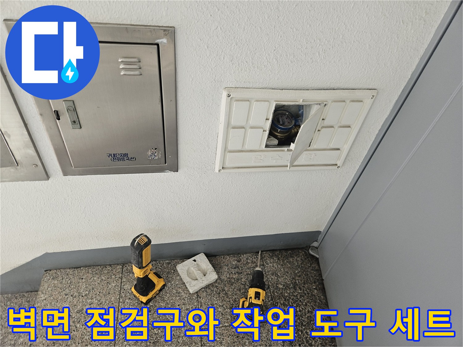 배관 내부 진단을 위해 벽면 점검구 앞에 배치된 전동 드릴과 공구