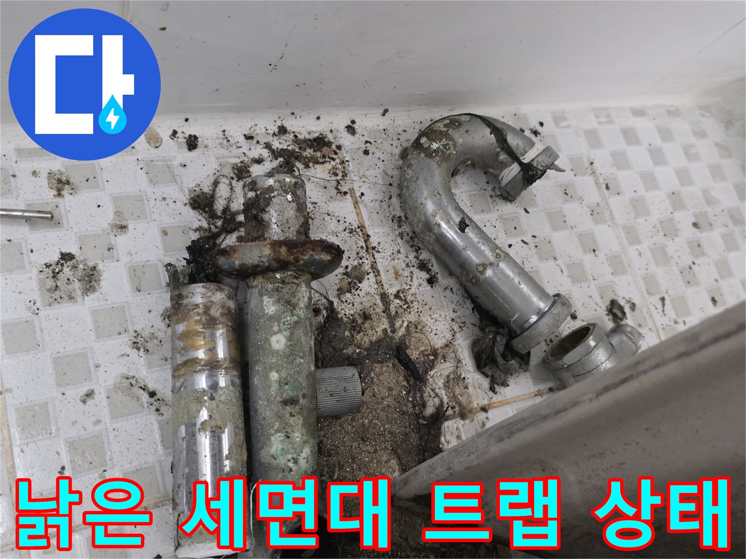 노후된 배수 트랩의 파손 부위와 주변 오염을 근접 촬영한 사진입니다.