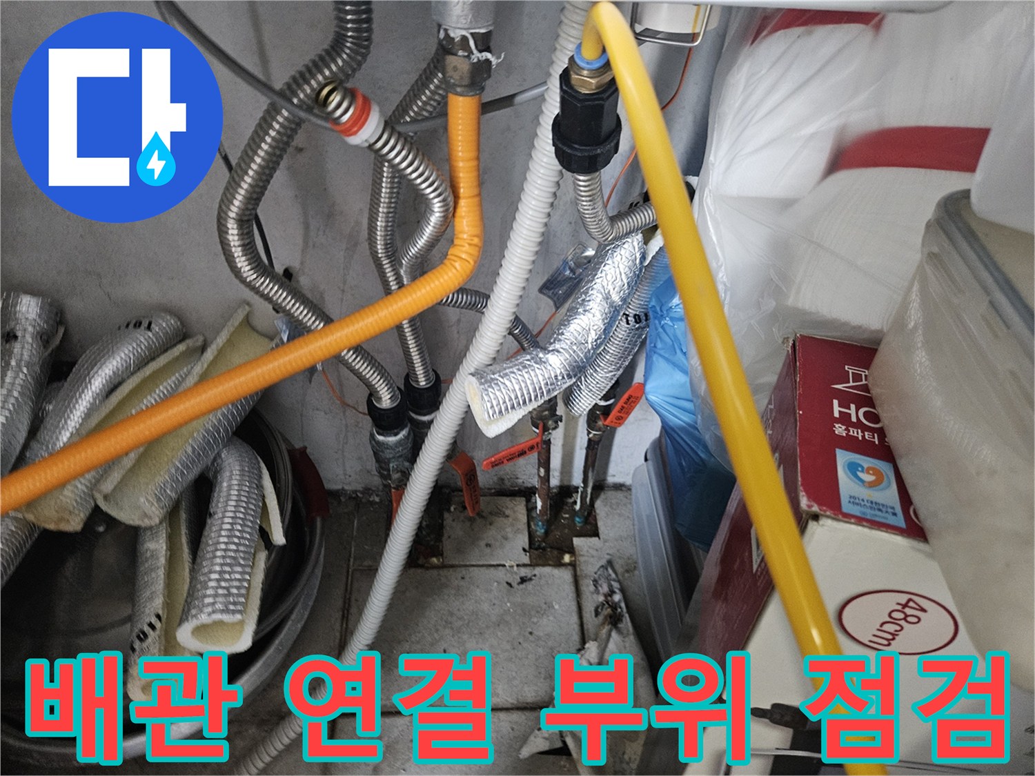 은색 주름관과 노란색 호스가 얽힌 보일러실 하단 배관