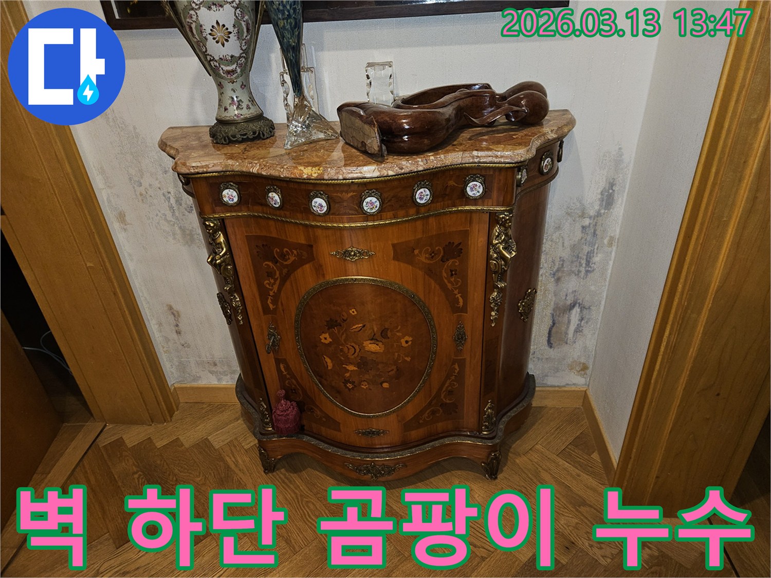 가구 뒤 벽 하단에-누수로 인해 발생한-심한 곰팡이와-벽지 손상이 보이는 사진