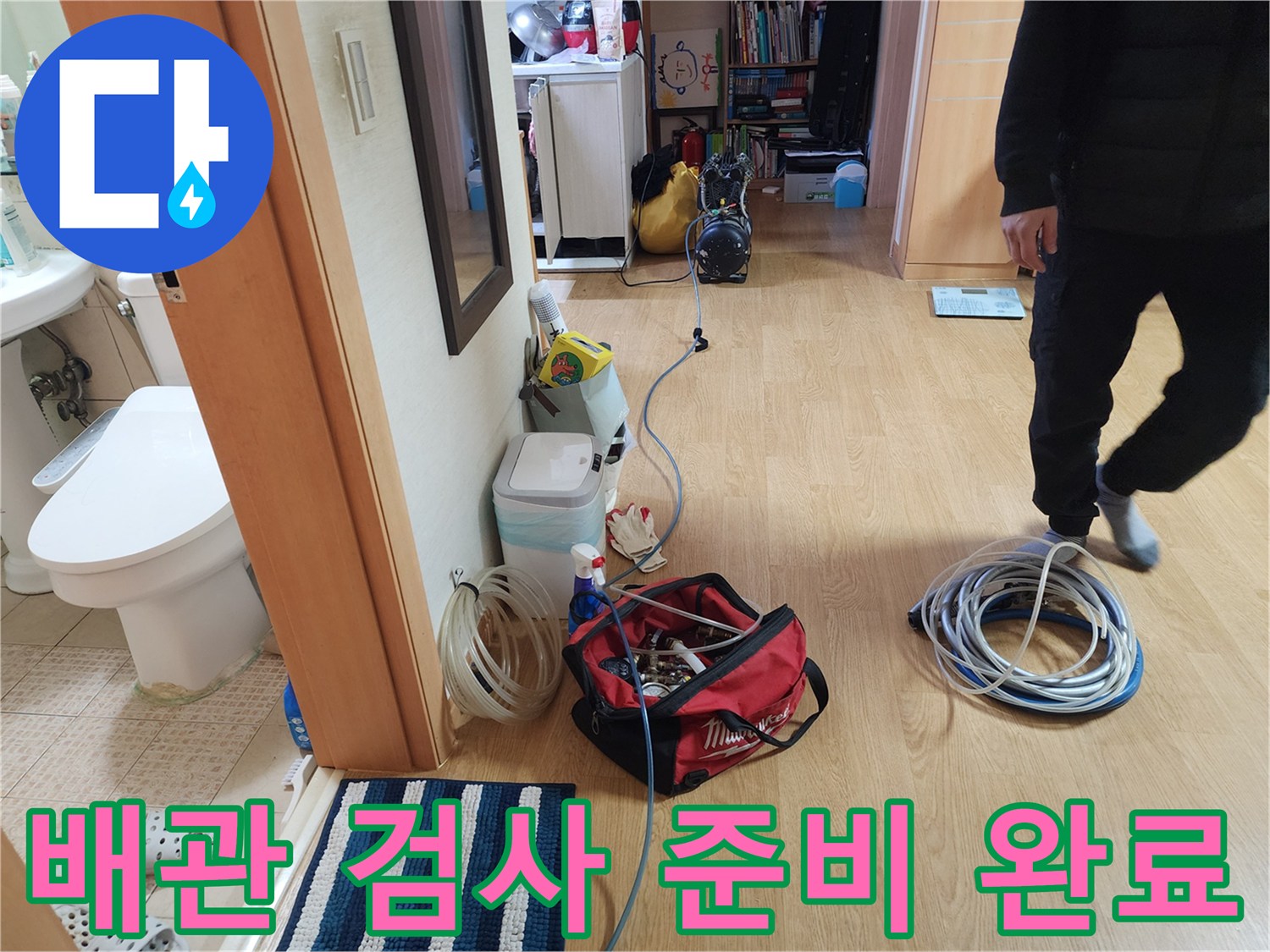 바닥에 놓인 공압 테스트 장비와 연결된 파란색 배관 라인