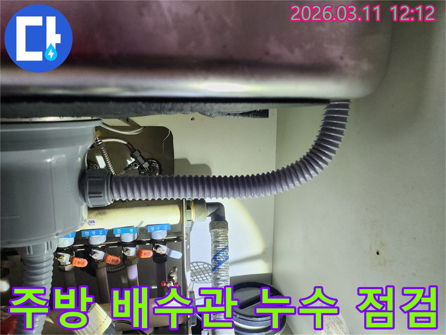 싱크대 하부장 내부의-배수관과 급수관-연결 부위를-세심하게 확인하는-엔지니어의 모습입니다
