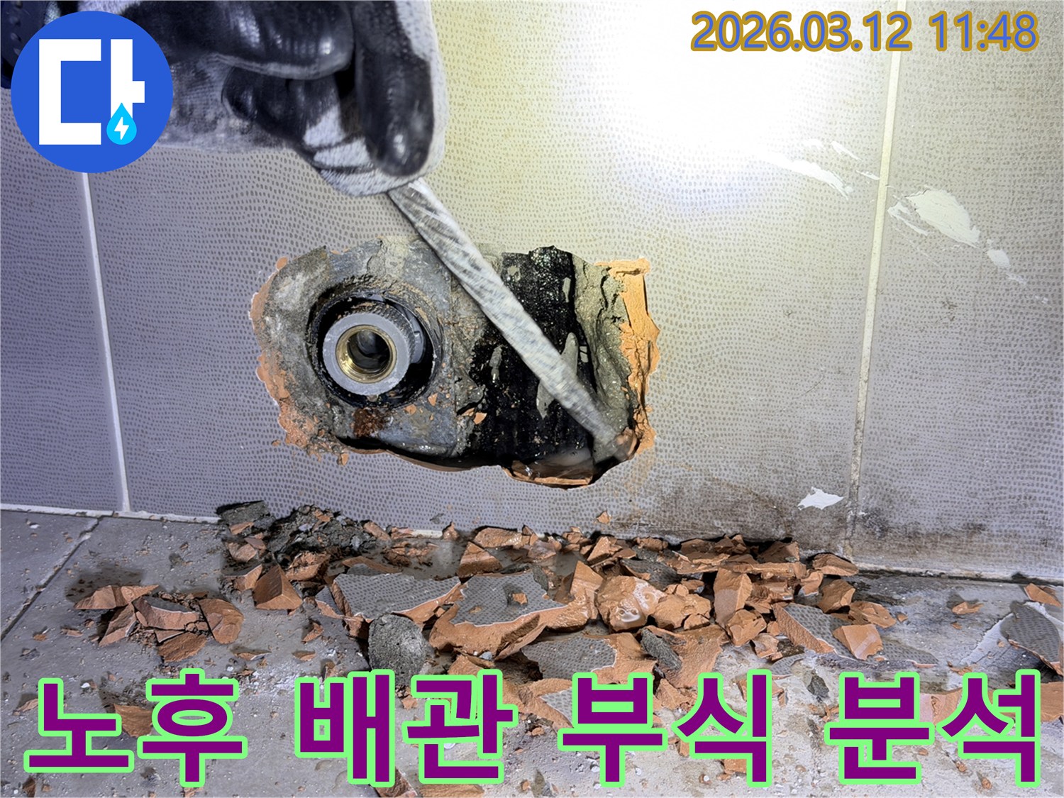 장갑 낀 손이-벽 속 노후 배관의 부식 지점을-정밀하게 분석하기 위해-해체하는 모습입니다