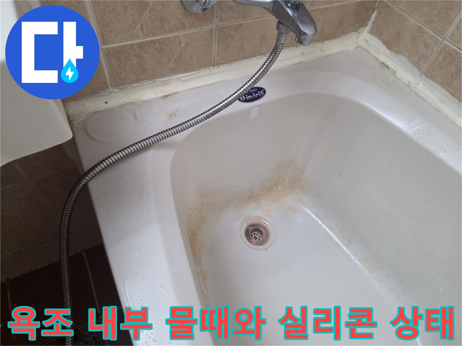욕조 내부 배수구 주변의 갈색 물때와 노후된 벽면 타일 사이의 상태를 보여주는 사진