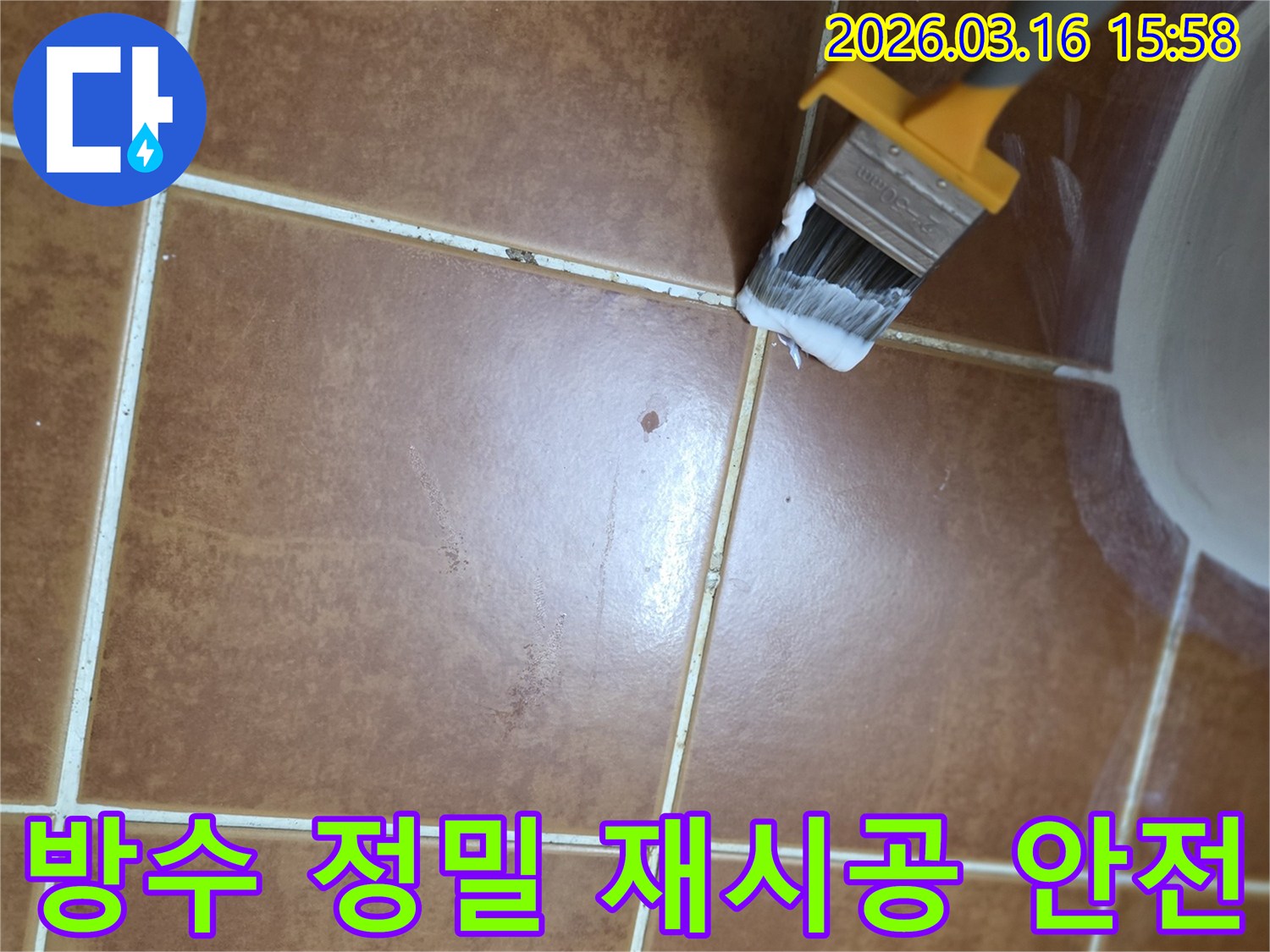 이 사진은-오래된 아파트 욕실 바닥의-타일 줄눈에-새로운 방수액을 바르며-누수 문제를 해결하고-방수 기능을 정밀하게-재시공하는 작업 과정을 보여줍니다.