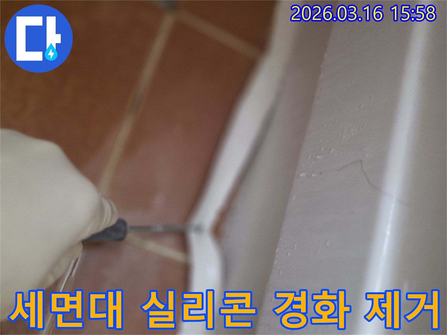 주거 공간 세면대 하단의-오래되고 경화된 실리콘을-전문가가 제거하는 작업 현장