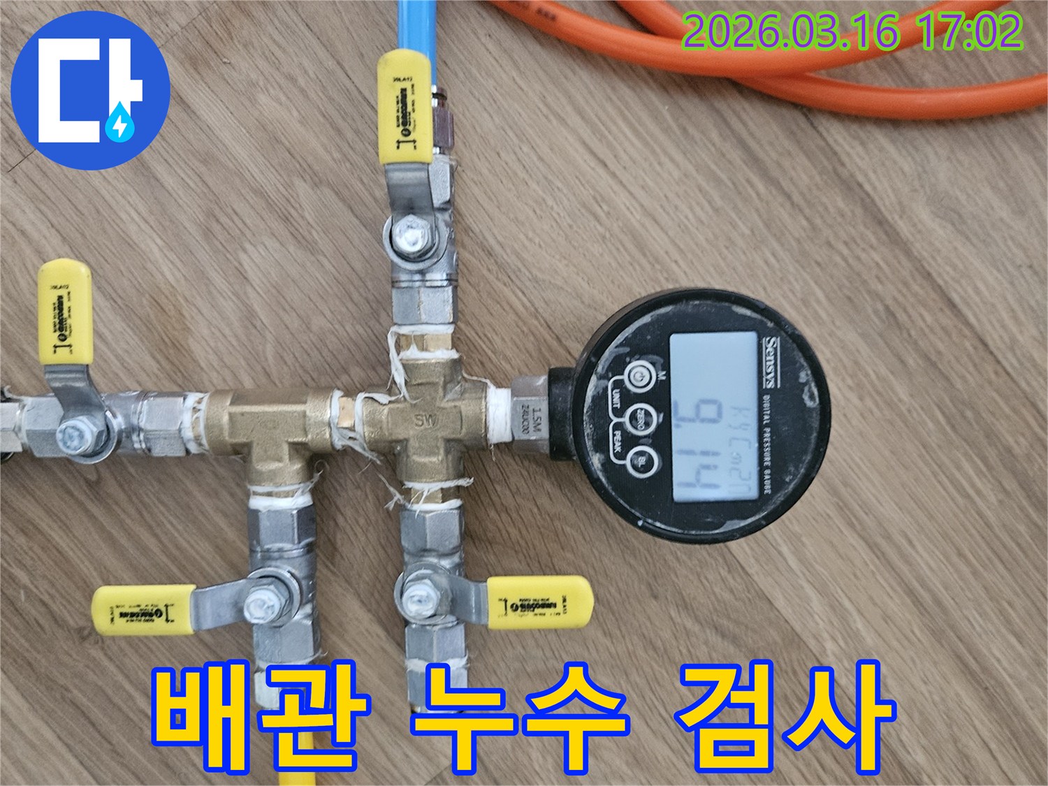 누수 탐지 전문가가-배관의 건전성을 확인하고자-압력 테스트 장치를 설치하고-압력계의 수치를-주의 깊게 관찰하는-장면입니다.