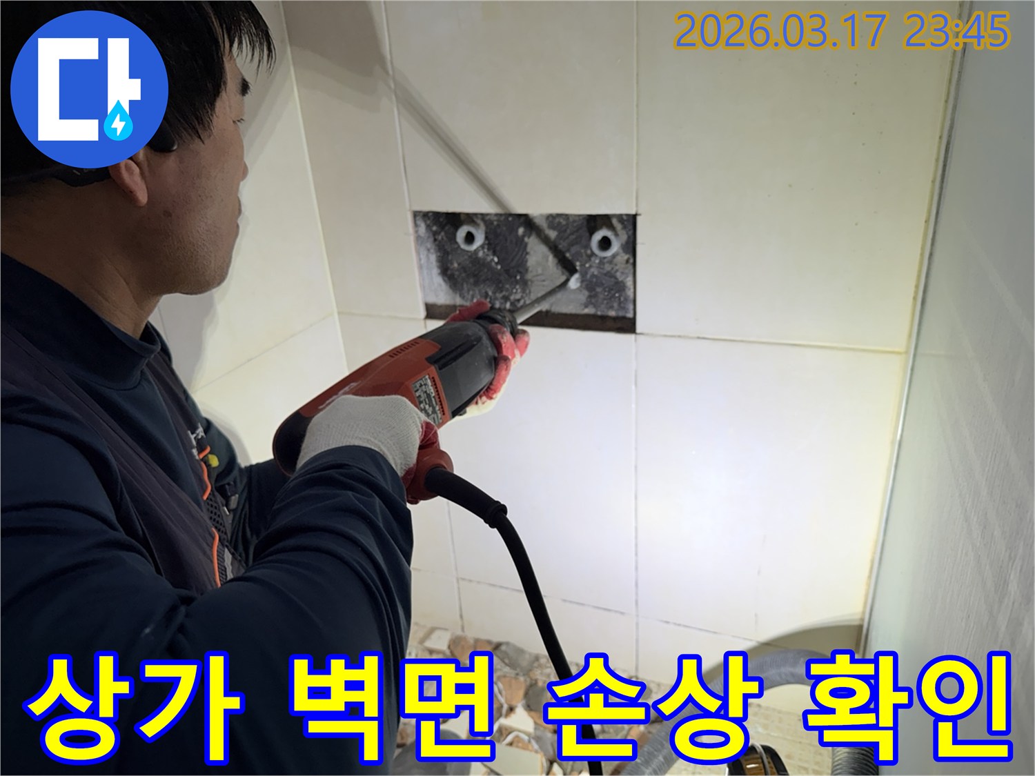 누수 전문가가 상가 벽면 타일을 깨끗하게 파쇄하며-누수 원인인 배관의 손상 여부를 육안으로 확인하는 작업을 진행 중입니다.