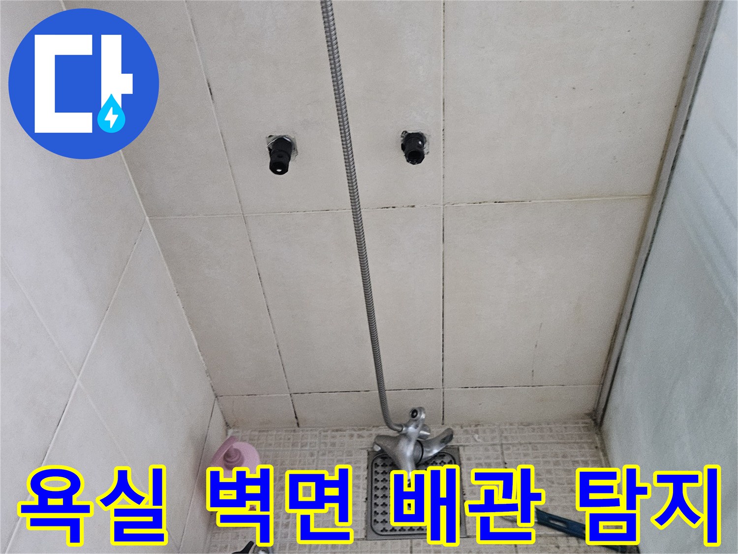 몽키스패너와 공구가 놓여 있는 화장실 수전 벽면 모습
