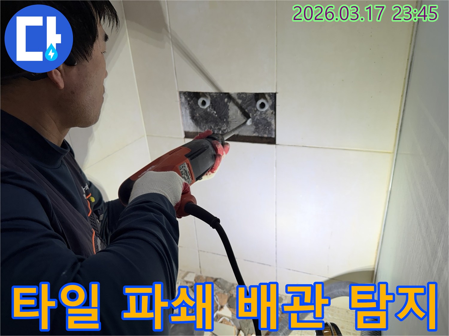 숙련된 기술자가 주택 누수 지점을 찾아내기 위해-벽면 타일을 깨고 내부 배관을 드러내어-정밀 탐지하는 작업을 진행하고 있습니다.