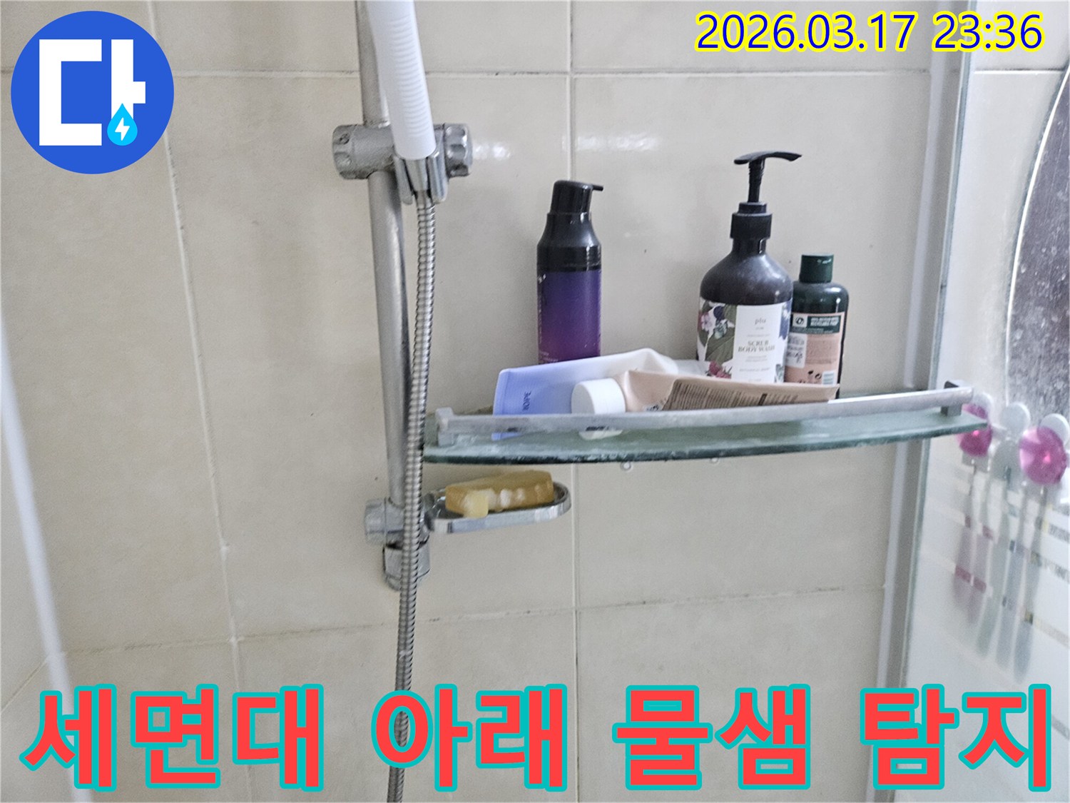 화장실 샤워기 옆-유리 선반에 맺힌 물방울은-세면대 아래 물샘의 간접적인 증거를 보여주는 이미지입니다