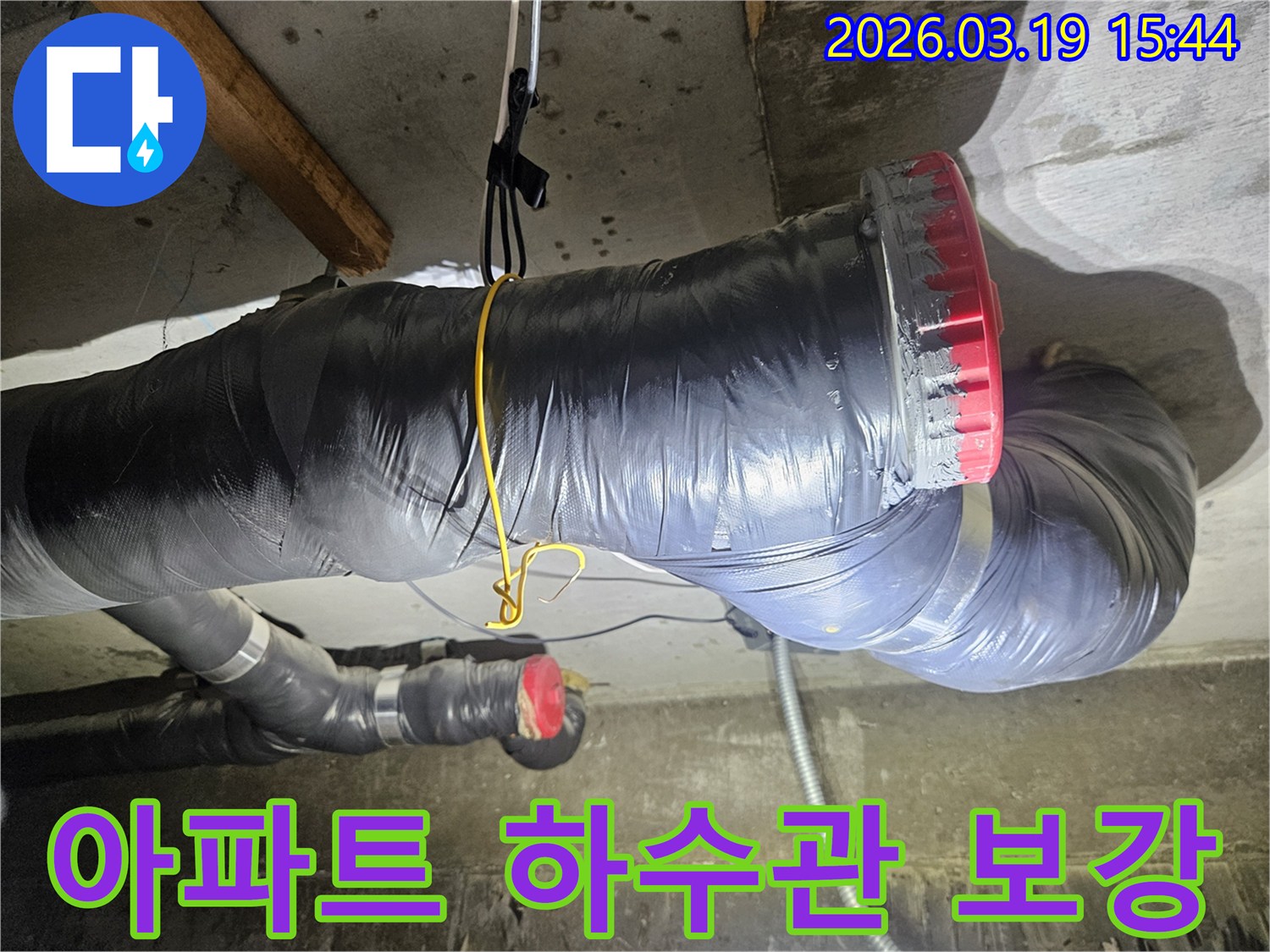 천장에 설치된 검은색 단열재로 감싸진 굵은 하수관과-그 옆으로 연결된 회색 파이프들이 보입니다