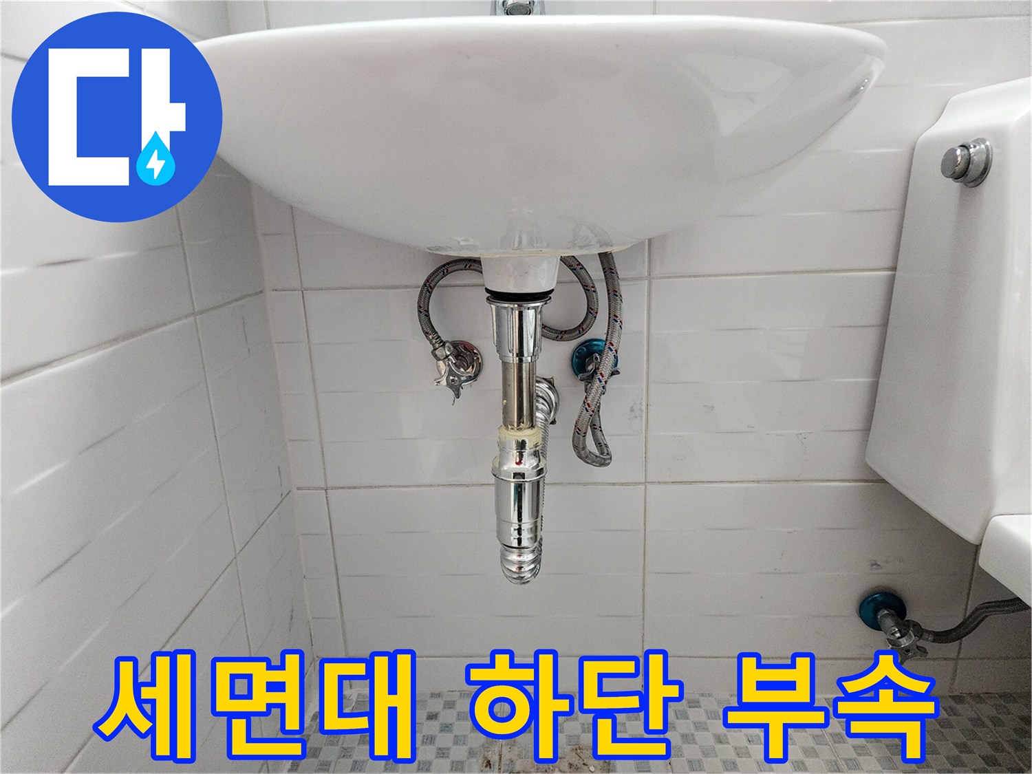 세면대 아래 벽면에 노출된 급수 밸브와 호스 연결부