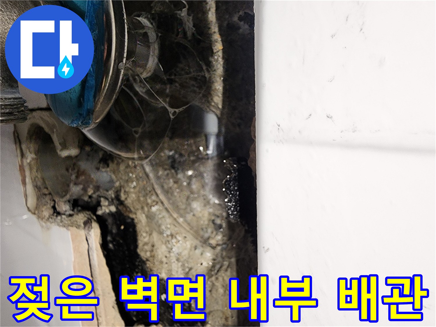 타일 제거 후 나타난 습기 찬 벽면과 수도 밸브 부위