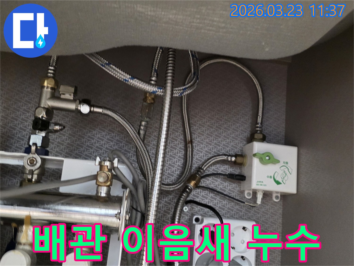 싱크대 하부장 내부의 수도-배관-이음새와 정수기-밸브-수도-호스-전기 콘센트가-보이는 곳에서-미세한 누수 흔적을-찾아내고 있습니다.