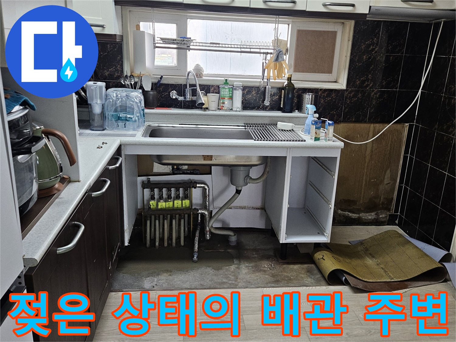 싱크대 하단 내부-분배기 주변에 고여있는 물기와 젖은 바닥재 모습