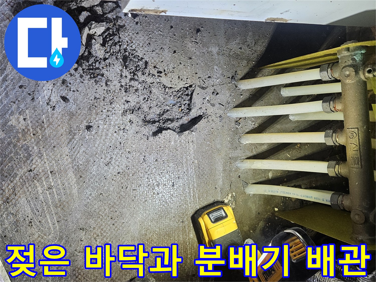 싱크대 하단 분배기 주변의 젖은 바닥과 작업 도구