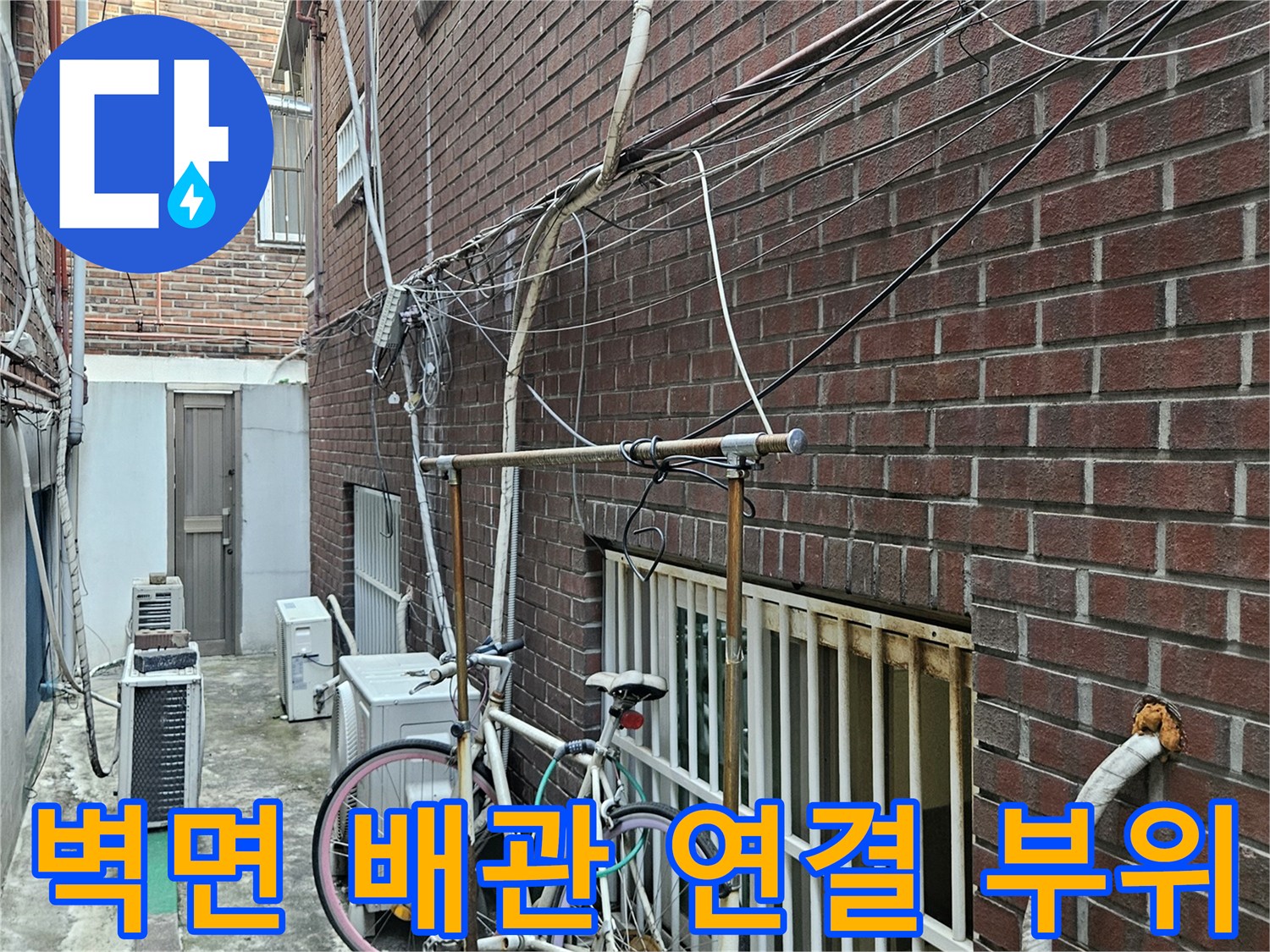 벽돌 외벽을 따라 설치된 배관과 실외기 주변의 설비 구조