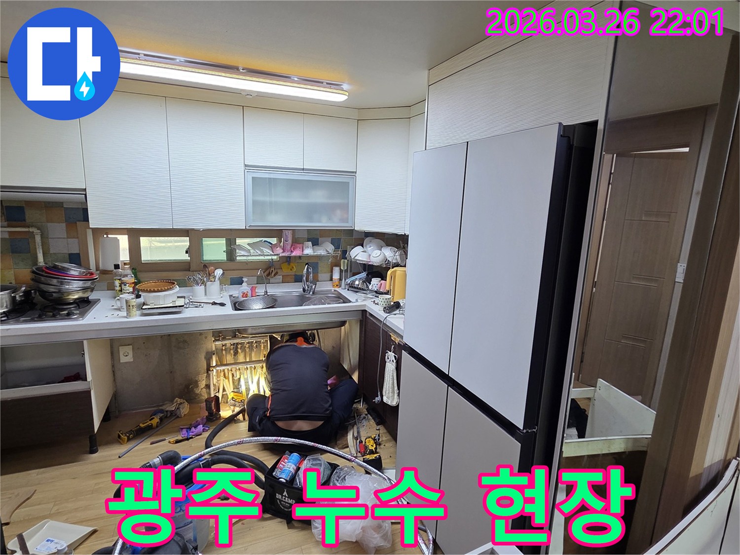 누수 전문 기술자가-싱크대 아래 좁은 공간에서-배관을 점검하고 수리하는 장면입니다