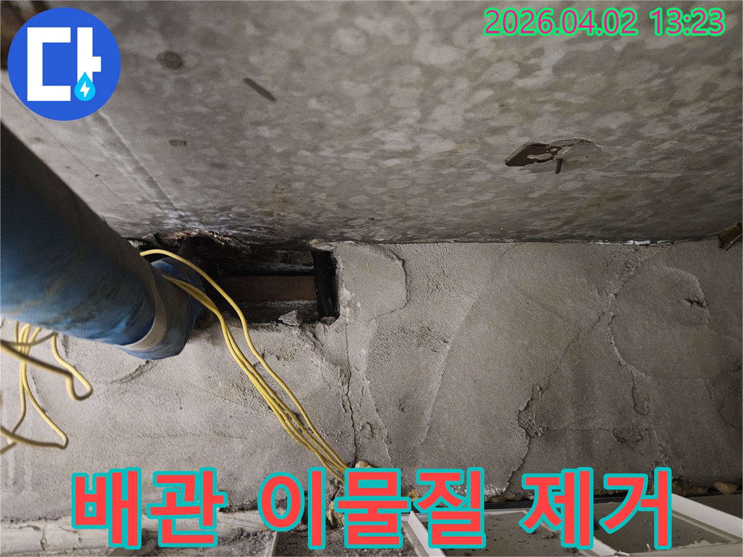 콘크리트 벽면을-개방하여-파란색 배관과-노란색 전선-주변의-이물질을-제거하는-누수-보수-현장입니다.